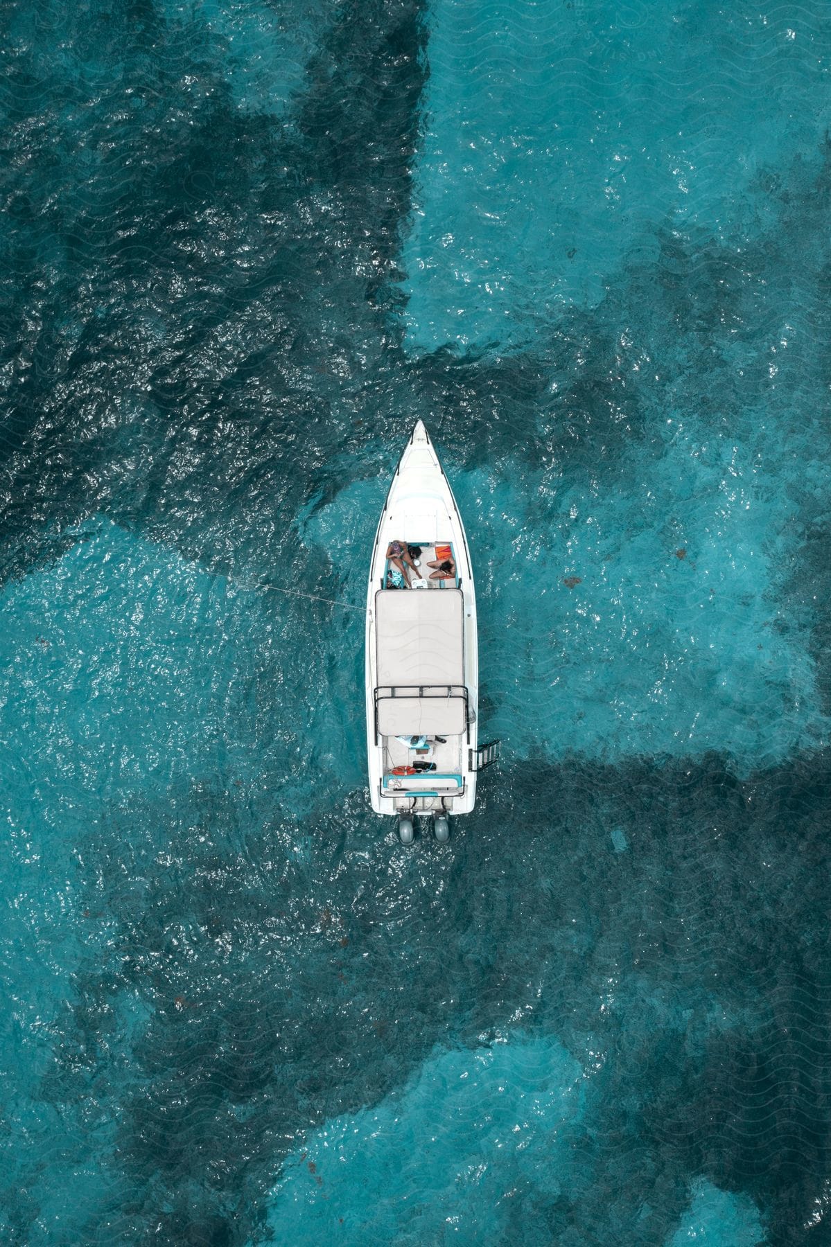 People sit in yacht on translucent blue ocean water.