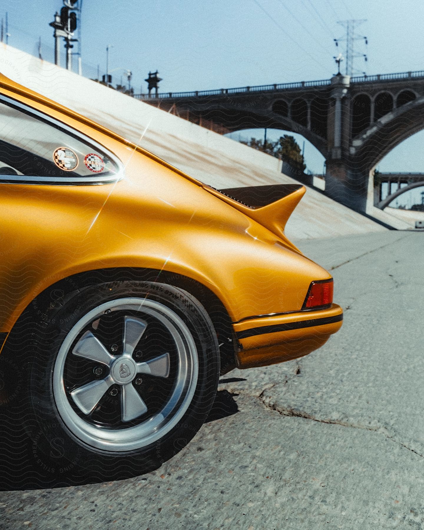 Orange backend of a sports car parked under a bridge.