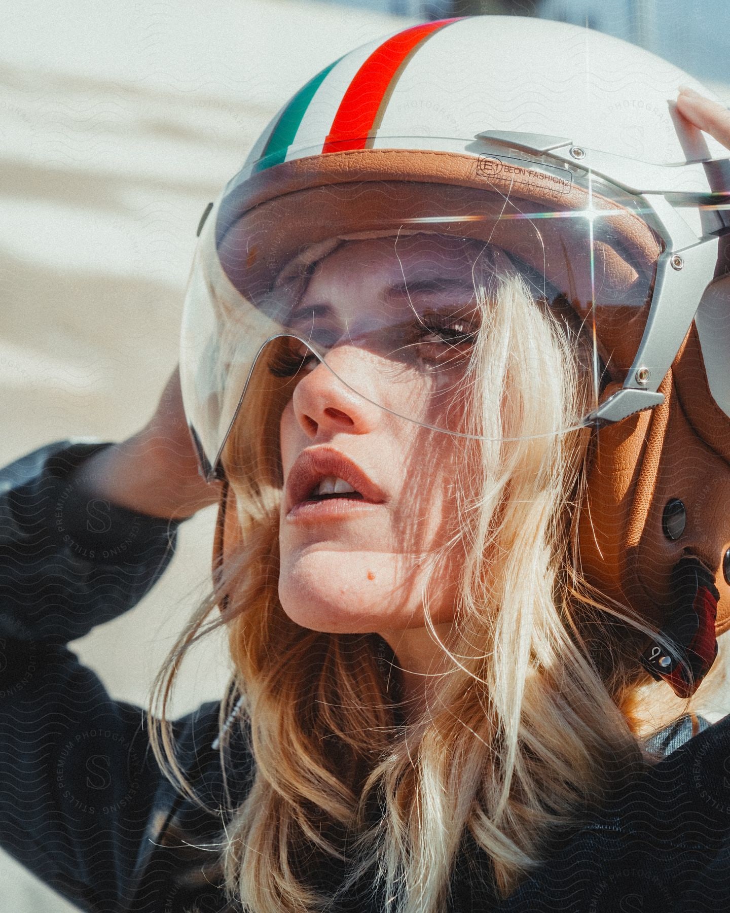 Stock photo of a blonde woman putting on a racing helmet.