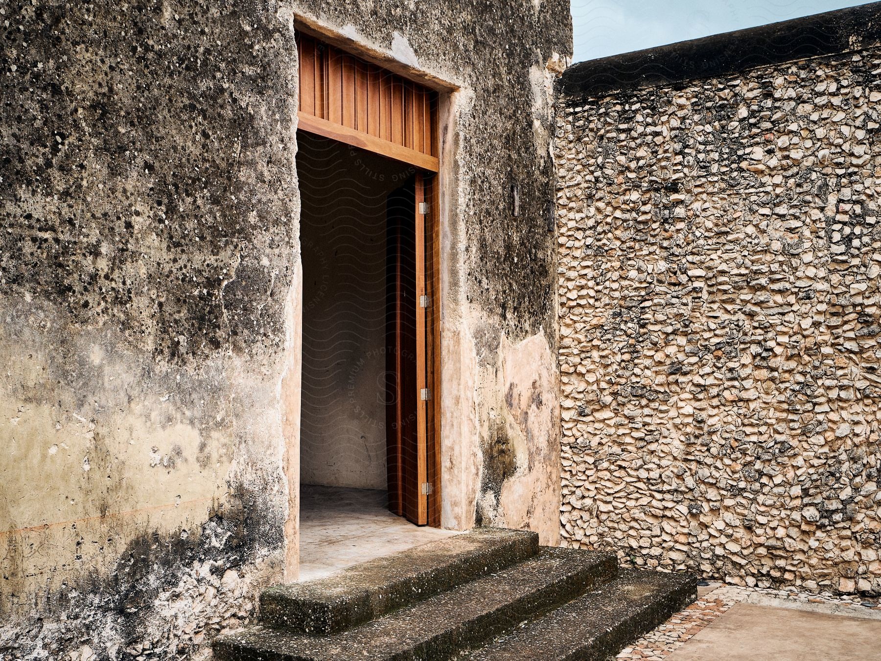 External architecture with a wooden door and a stone wall.