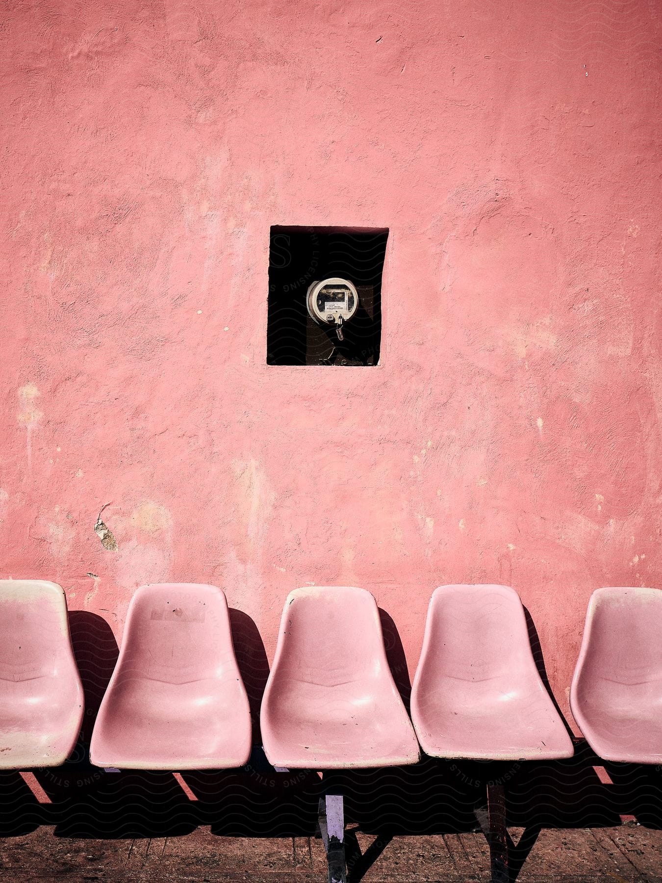 Architecture with pink walls and also pink plastic chairs.