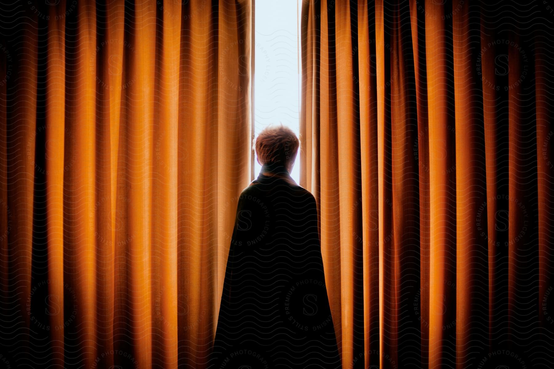 A Man Wearing A Cape Staring Out Of A Window