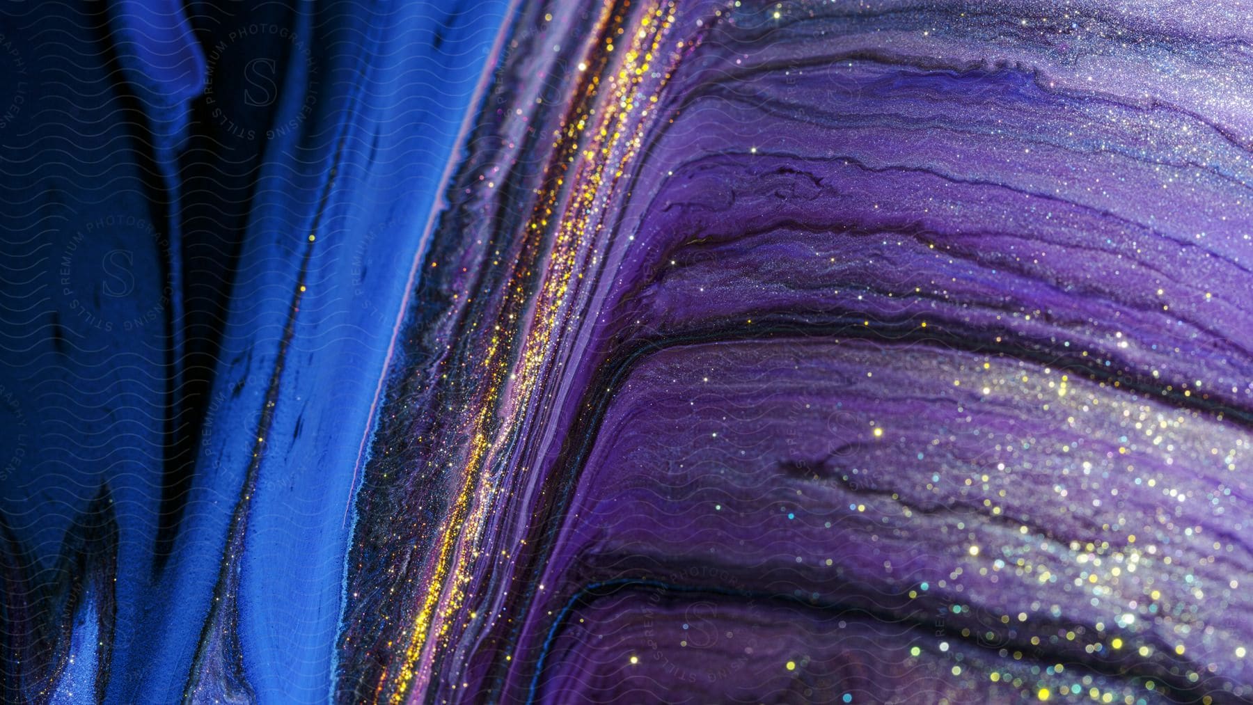 A blue and purple oil paint with a splatter of gold shine