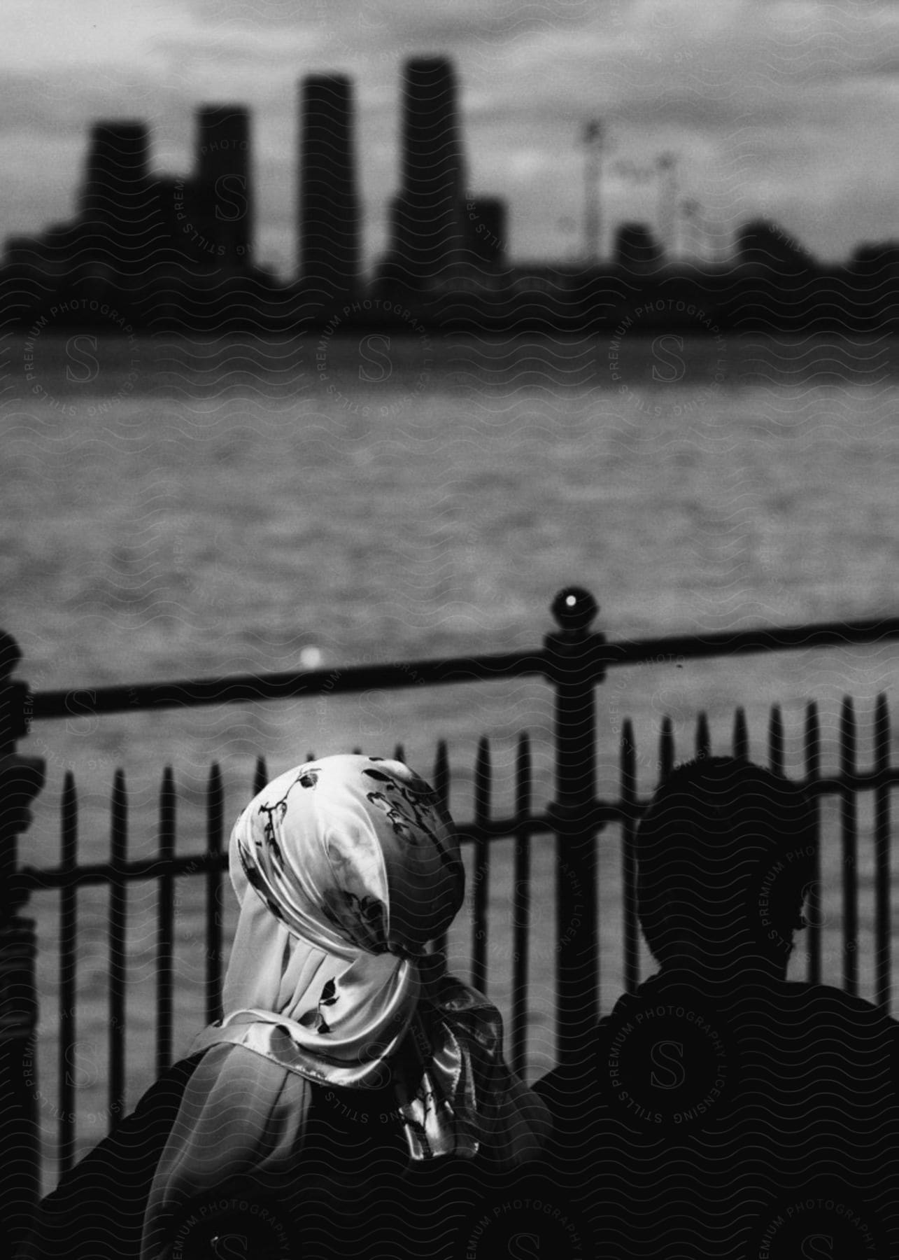 Two people sit on a bench looking at the waterfront city skyline