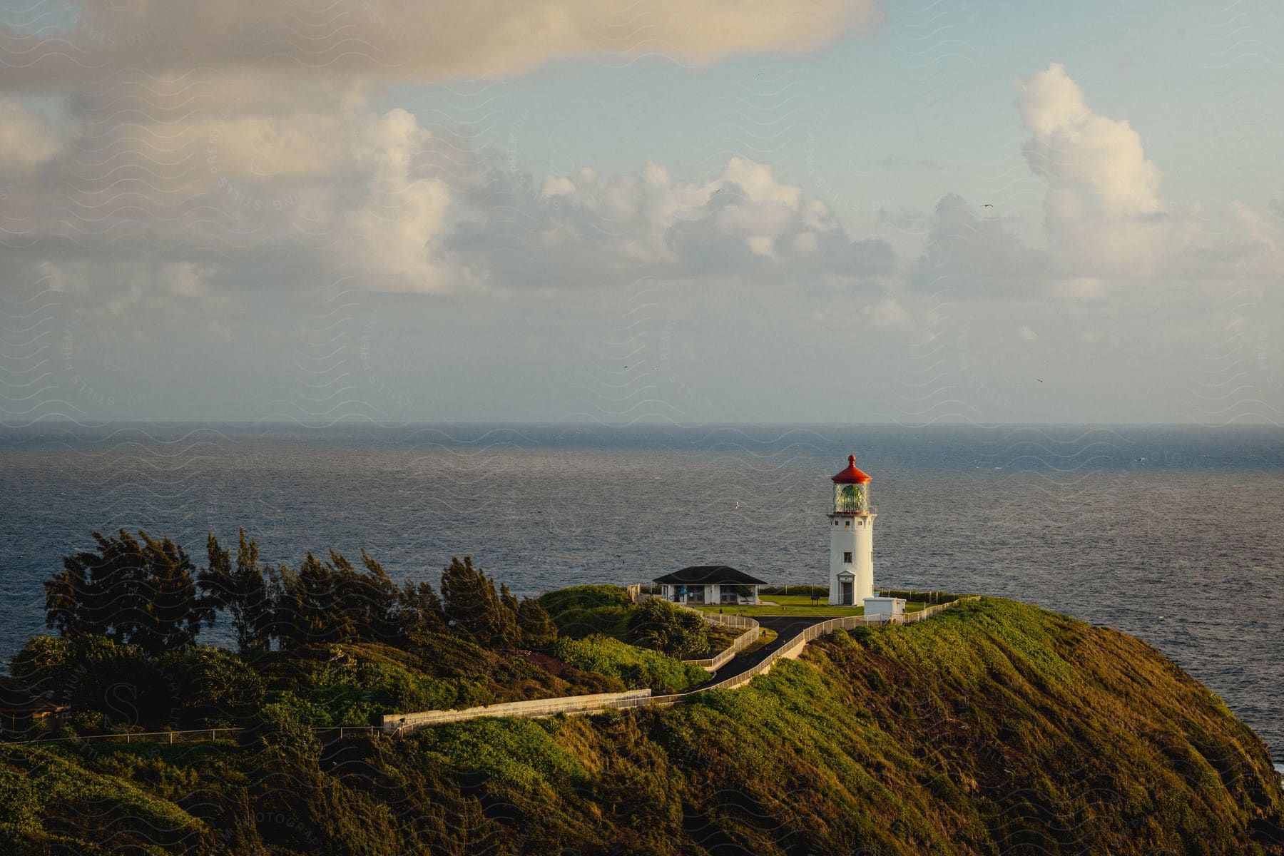 An aerial view of a lighthouse out on the cliffs overlooking the ocean.