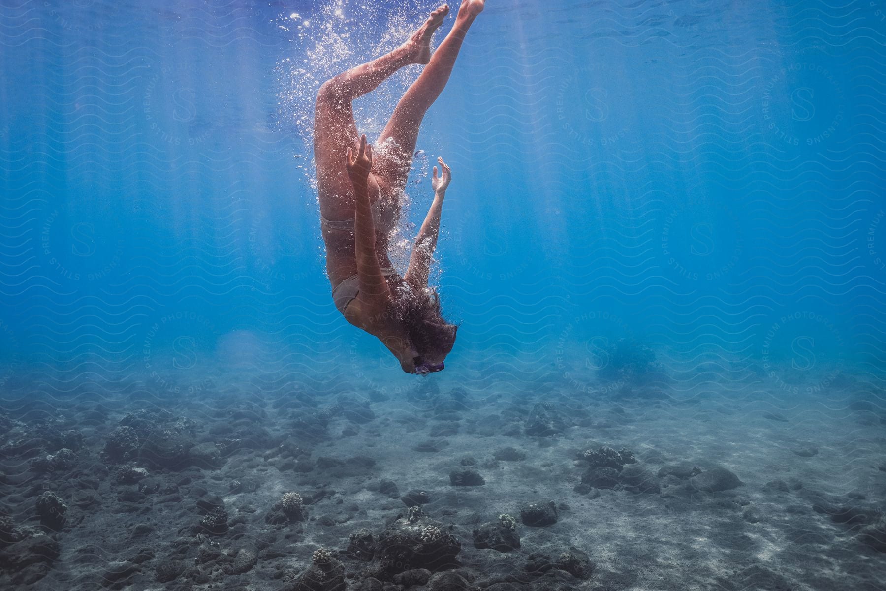 A Woman In A Bikini And Goggles Dives Underwater In The Shallow Ocean