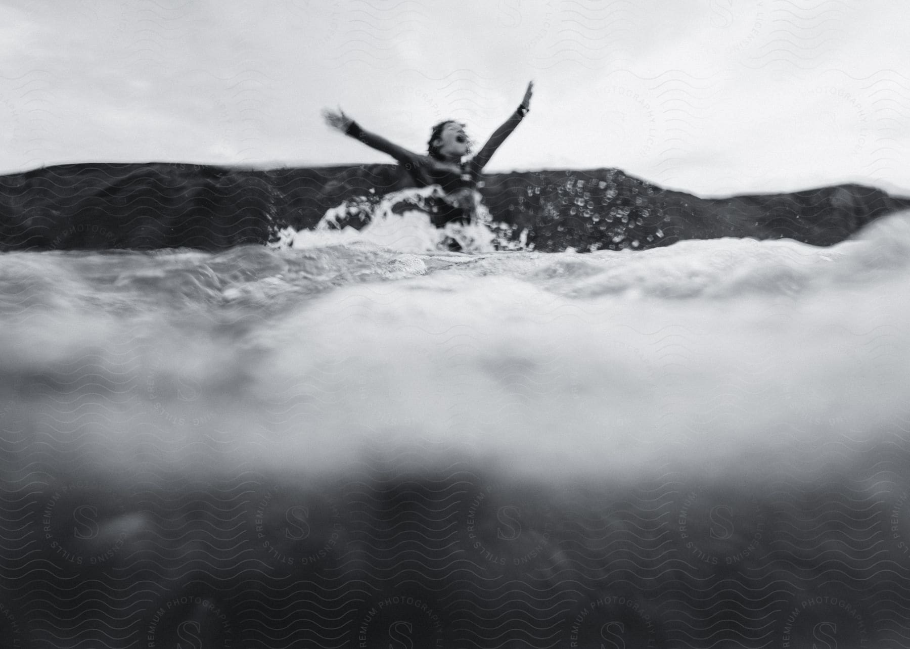 A woman surfer jumping out of the water and cheering