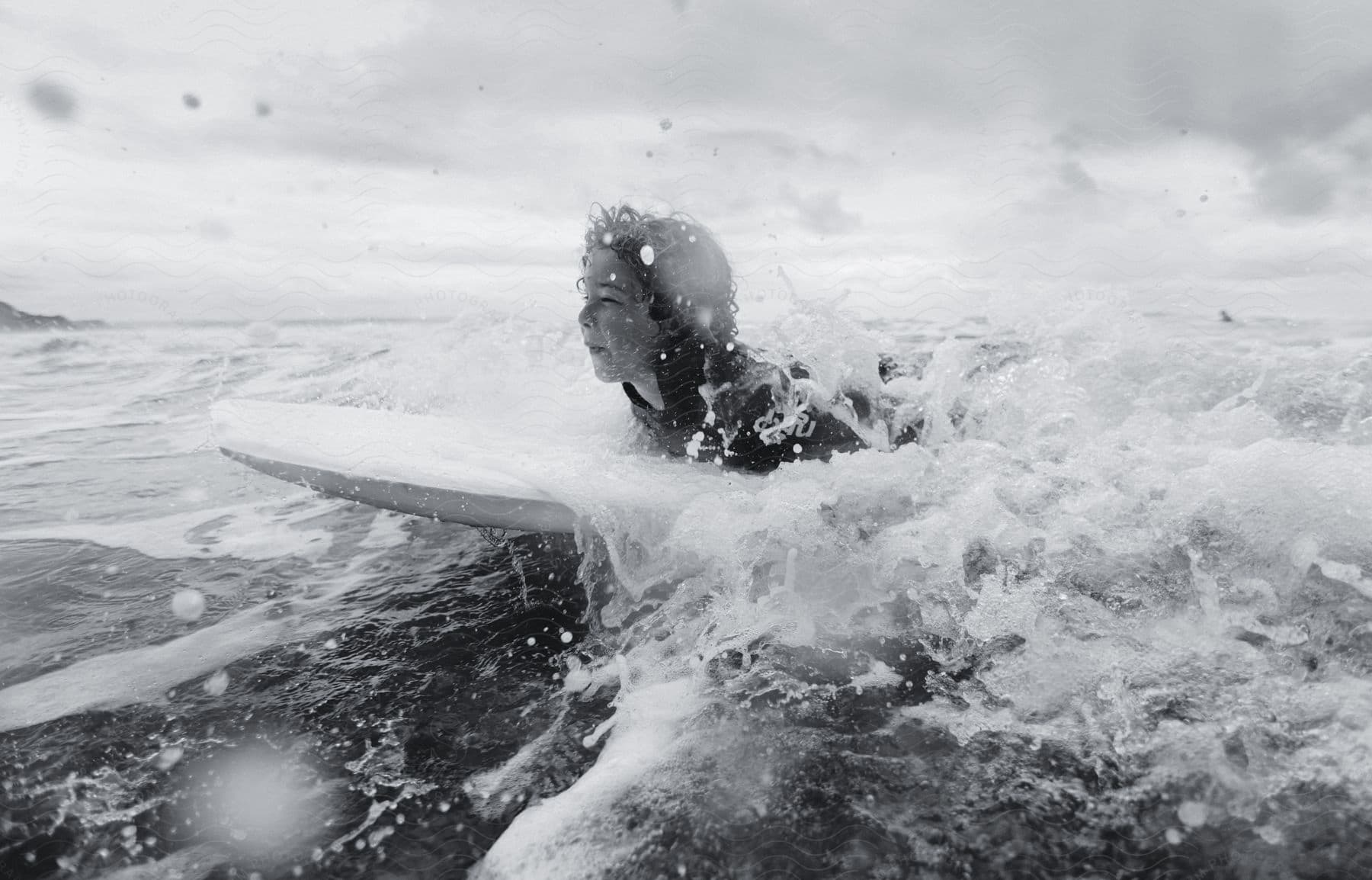 a woman lies on her stomach while paddling on her surfboard