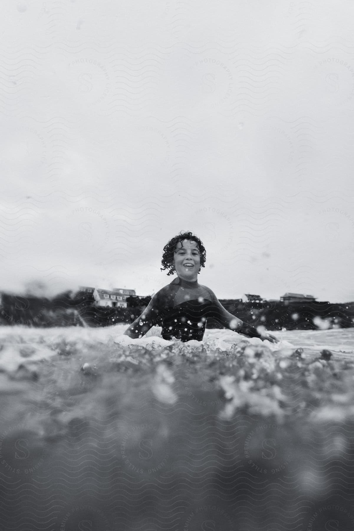 A child surfer standing in the waves in the ocean
