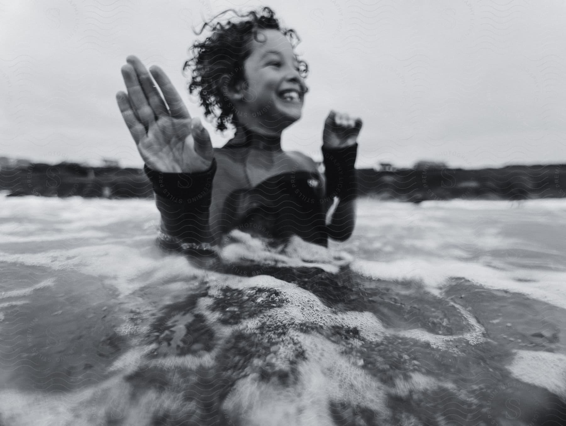 A boy wearing a wetsuit in the sea.