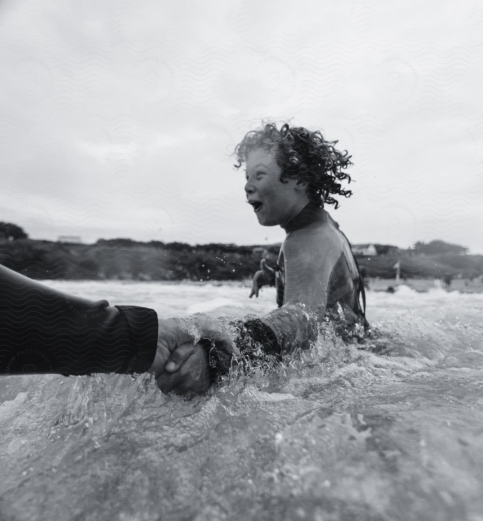 man holds excited girl’s hand walking in sea