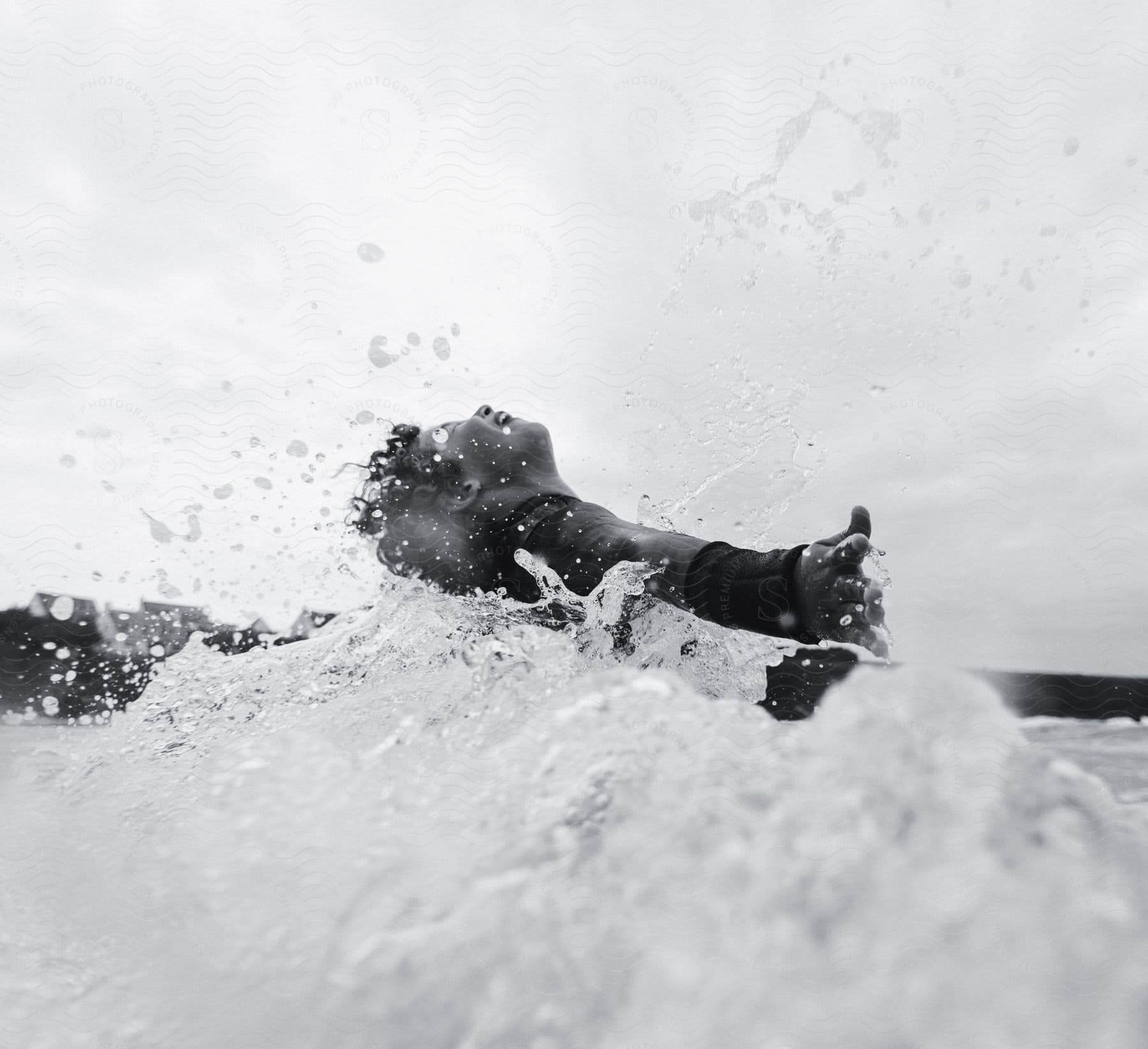 a man leans his back while surrounded by waves in the ocean