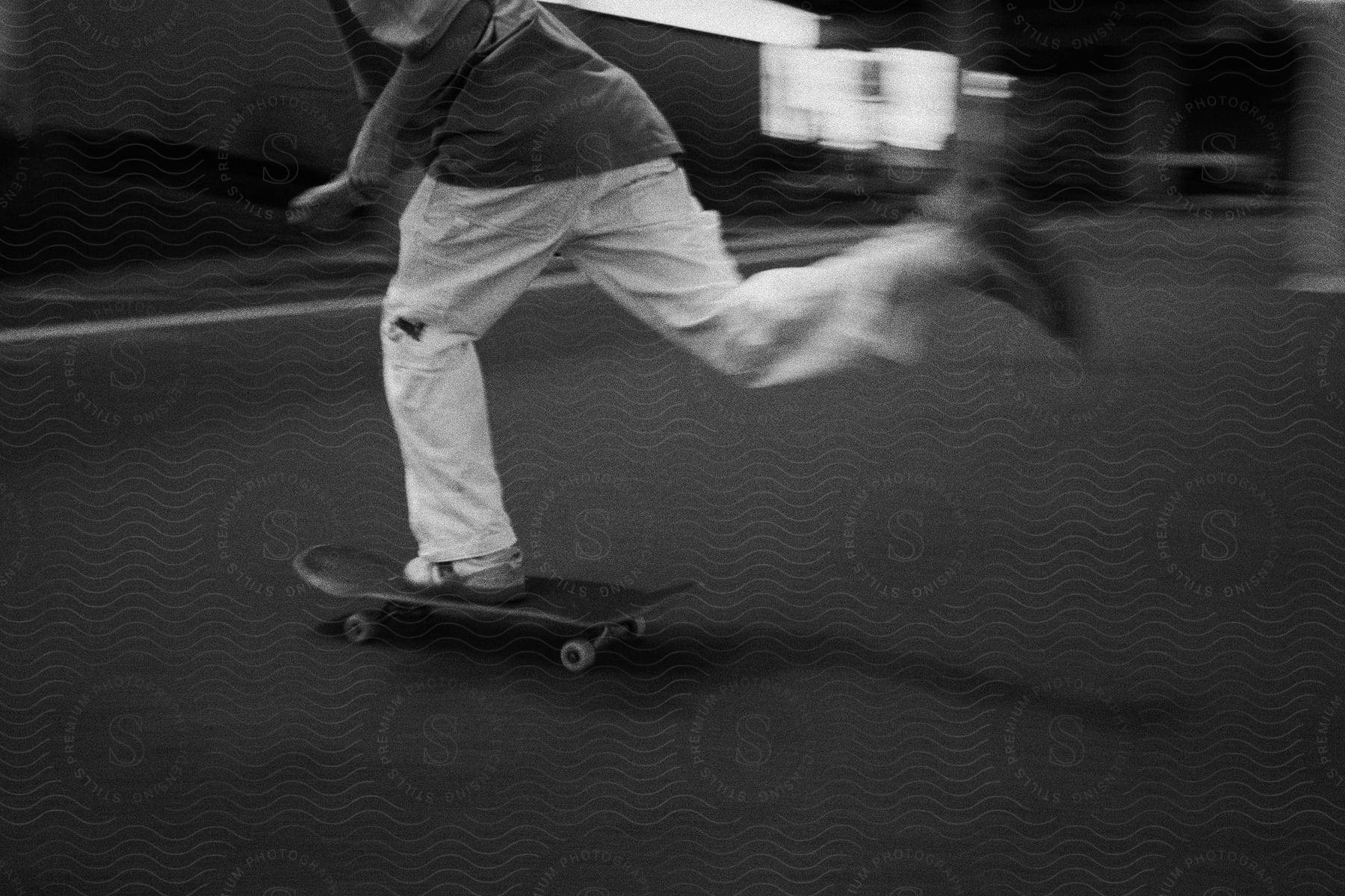 A man in white pants and a black shirt skateboards.