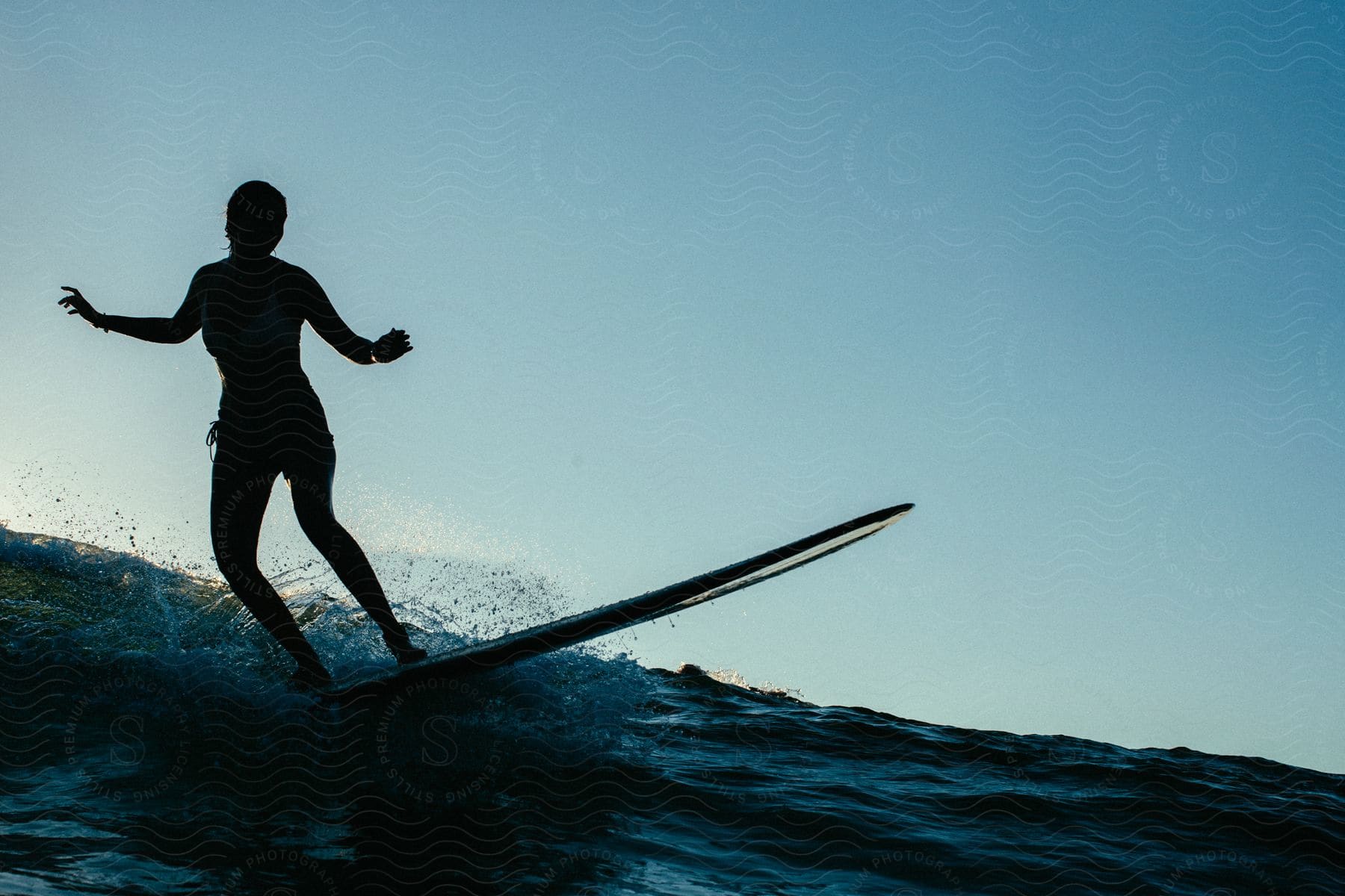 Water splashes as a surfer balances herself and rides a wave