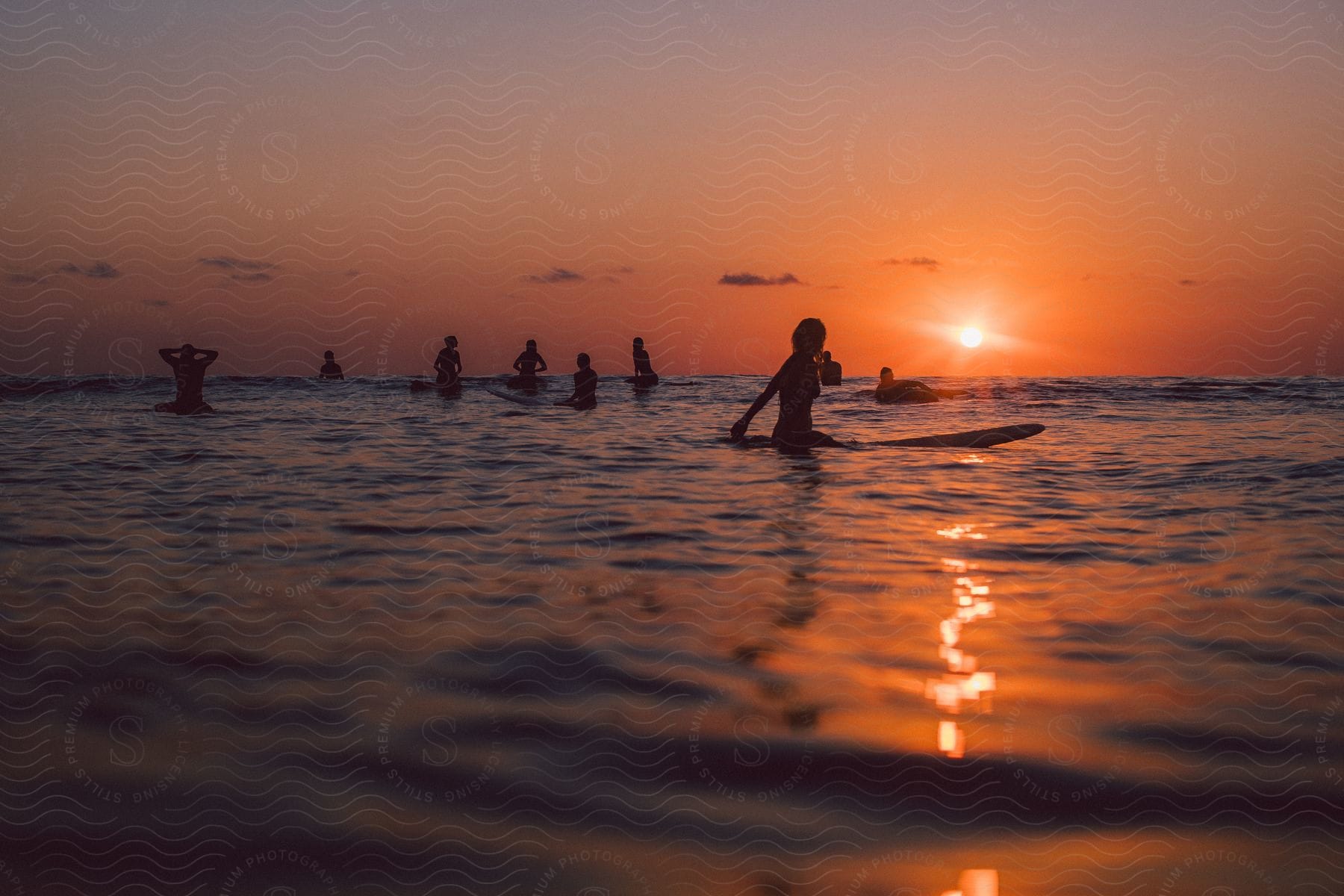 A few friends are sitting on their surfboards as the sun sets.