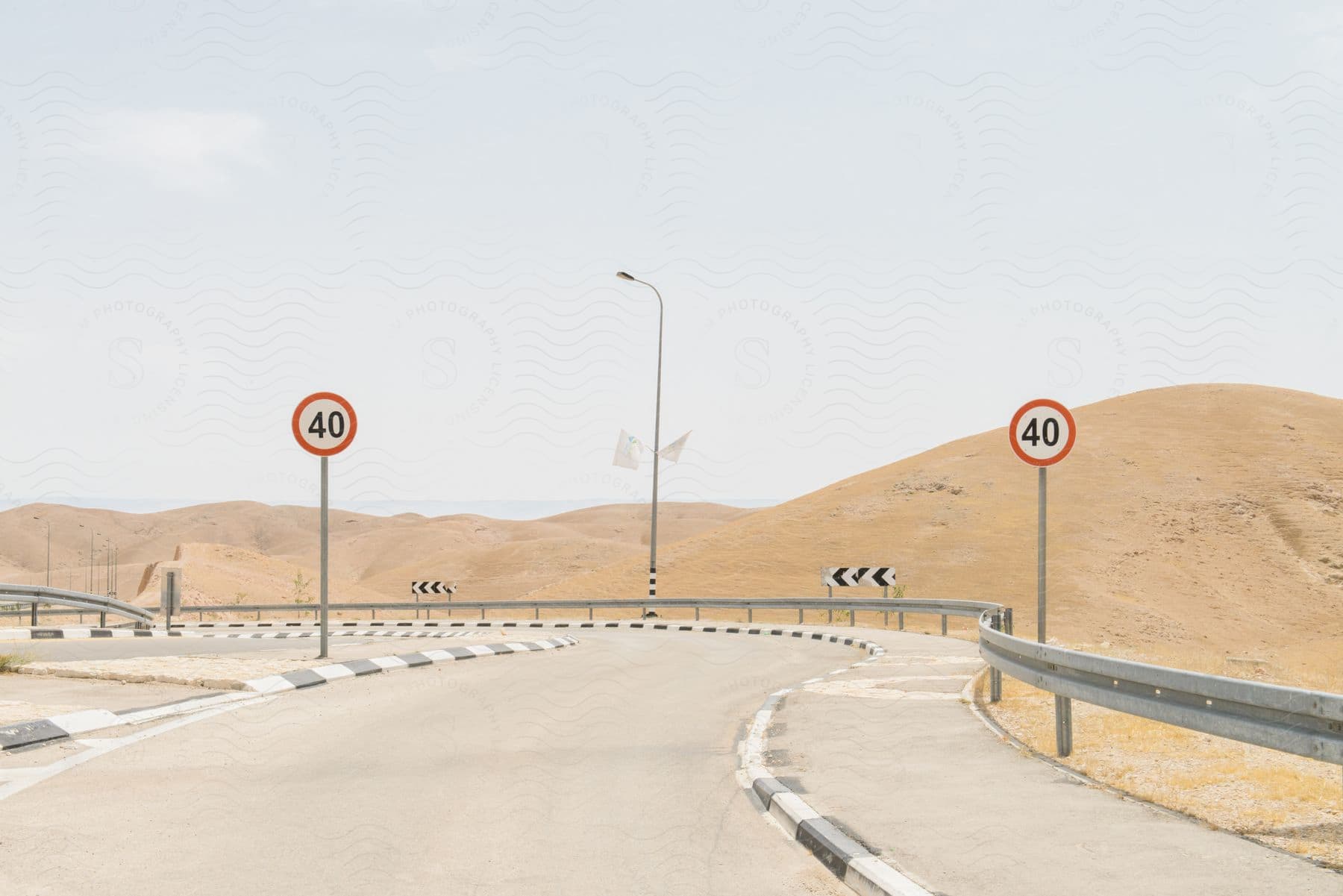 A desert road curves near hills with signs on the roadside