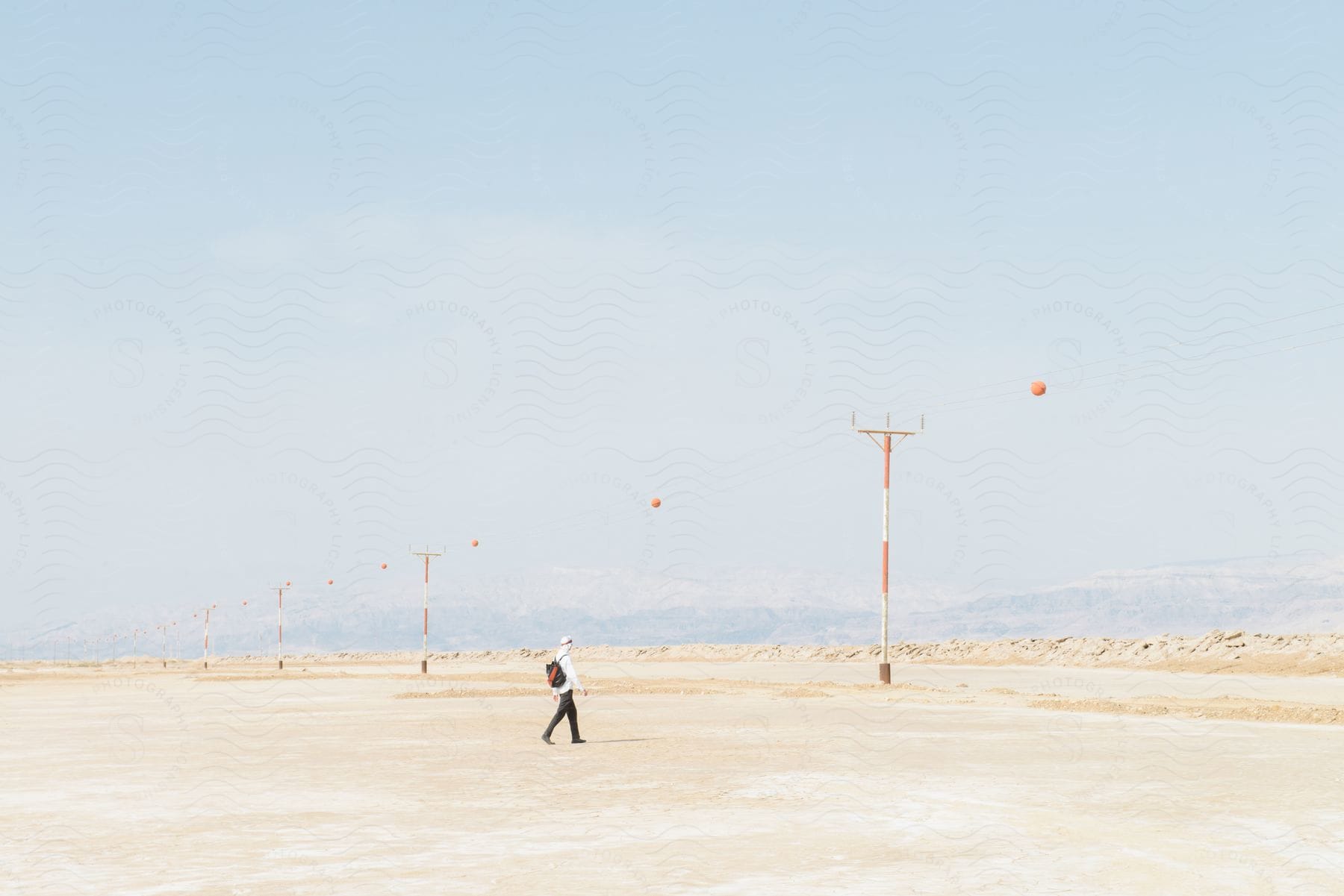 A person walks near power lines in the desert