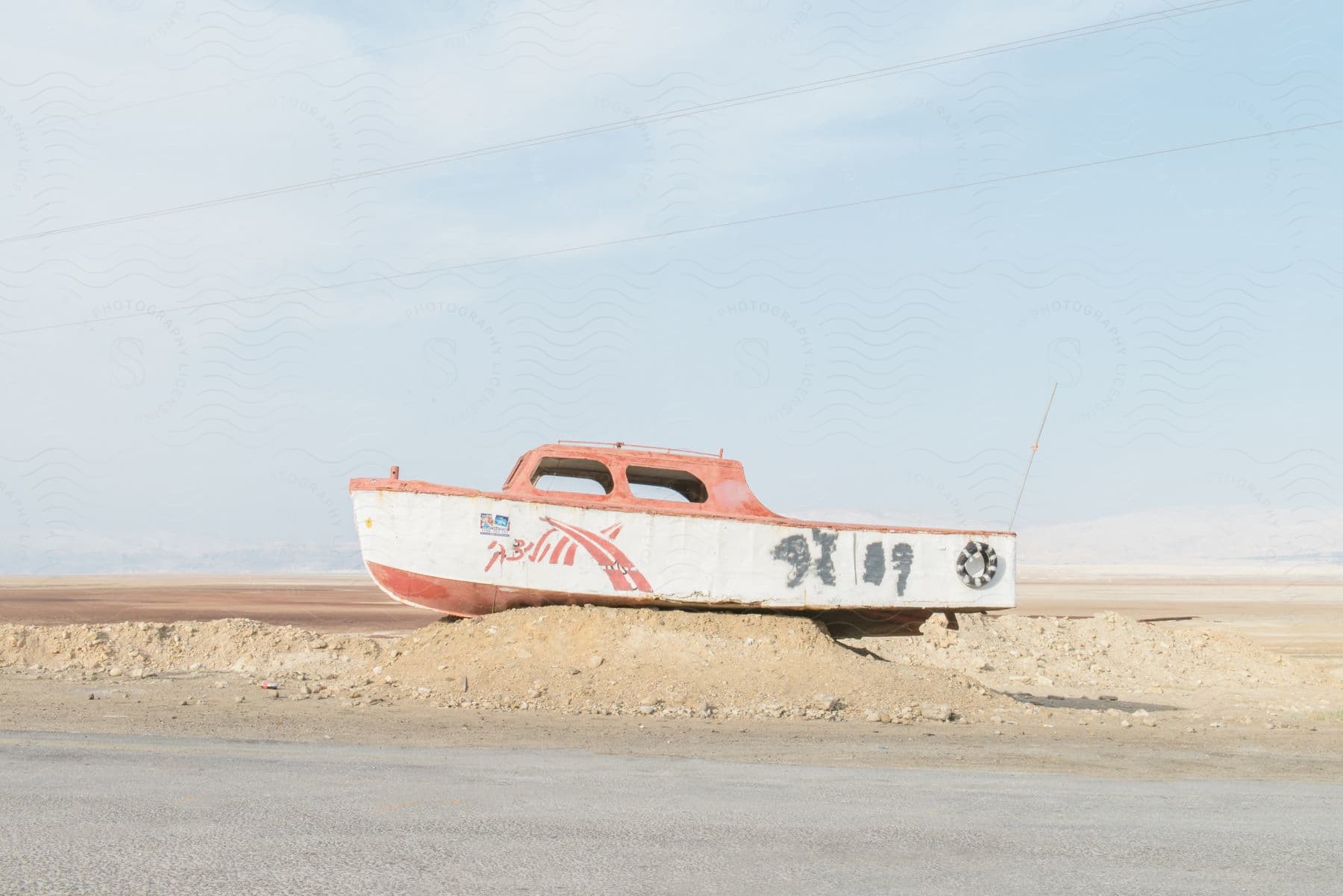 A boat sitting out on the dirt in the middle of the day stuck in place.