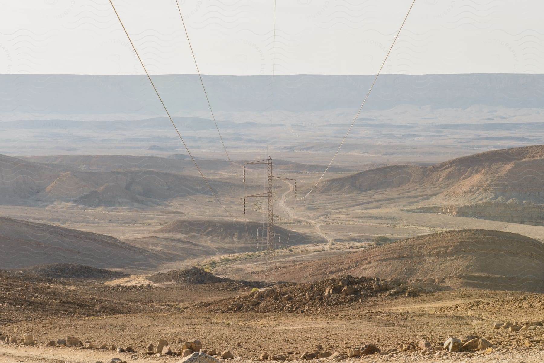 Transmission towers with overhead power lines on barren mountain slopes in the desert