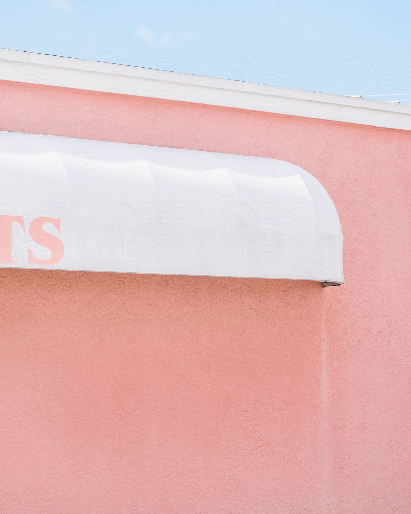 A white awning with pink writing on a pink wall.