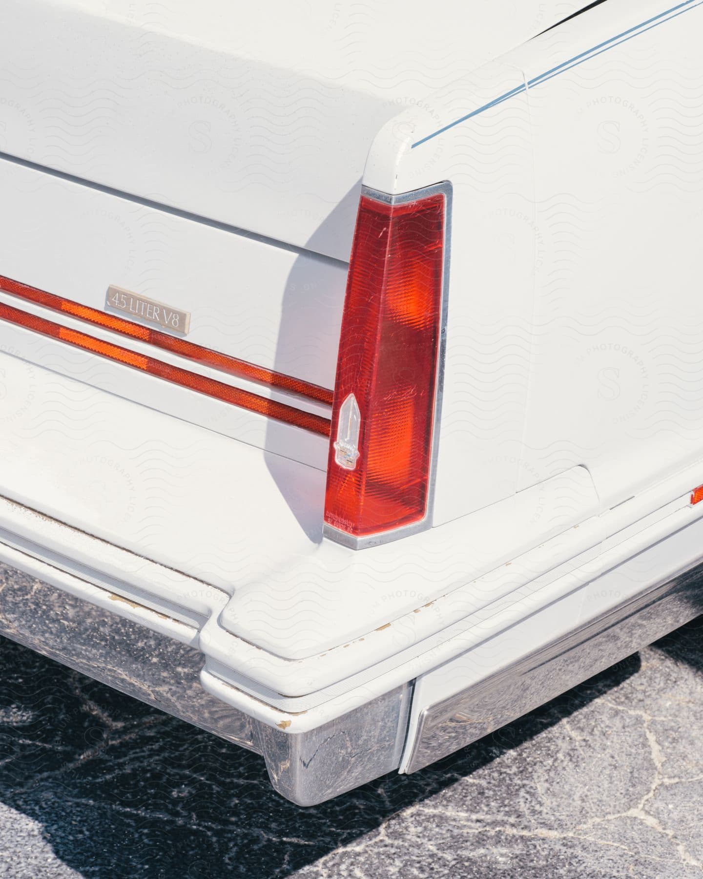 A white car with red tail lights outdoors on a sunny day.