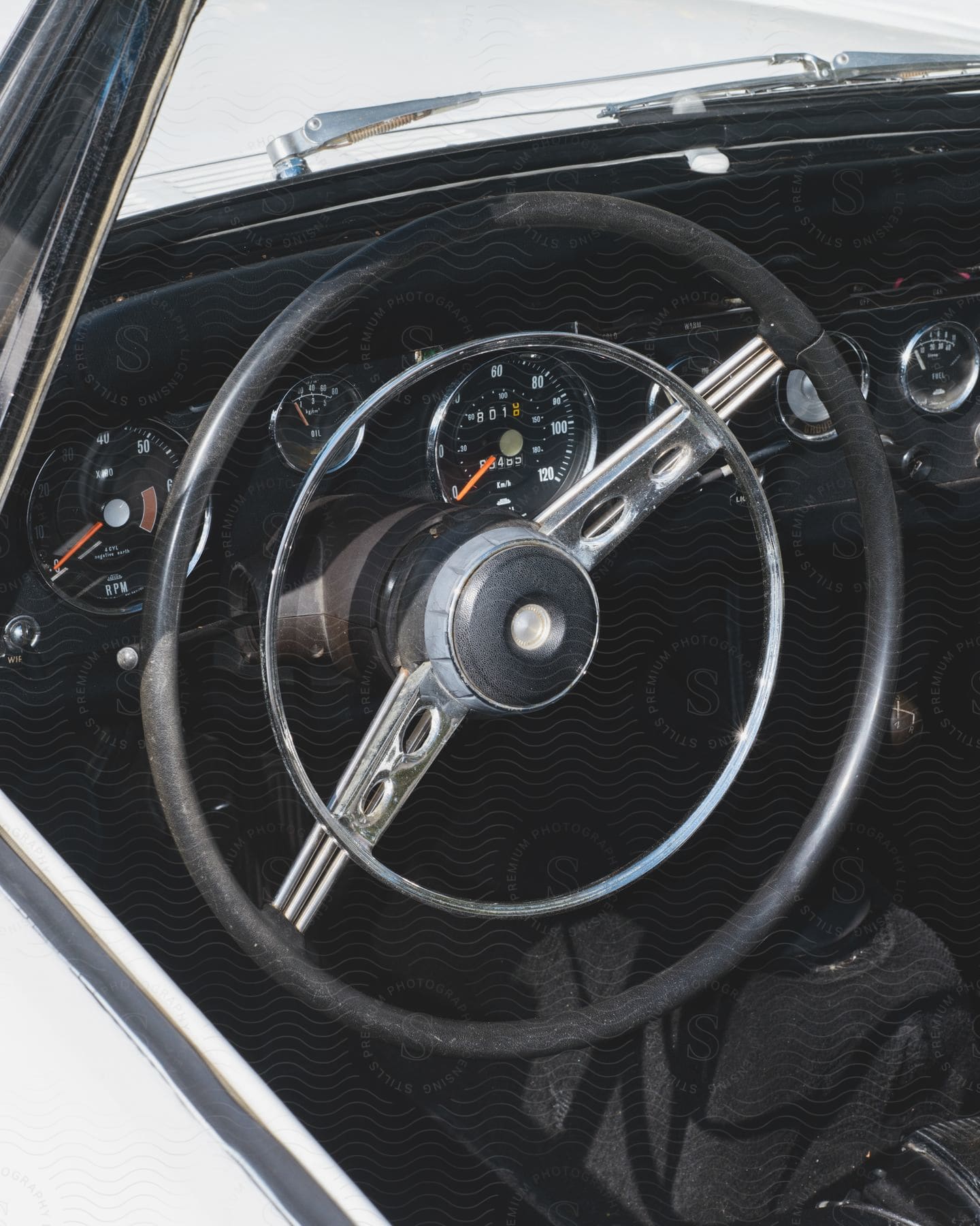 Inside an automobile the steering wheel is tilted in front of the gauges on the dashboard