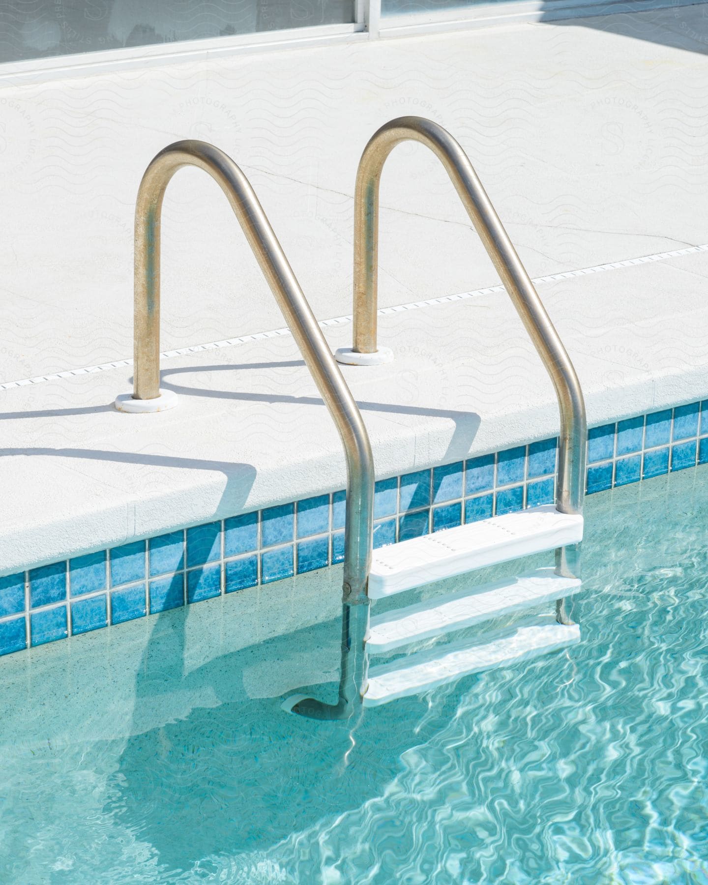 A swimming pool ladder has three steps in the water.