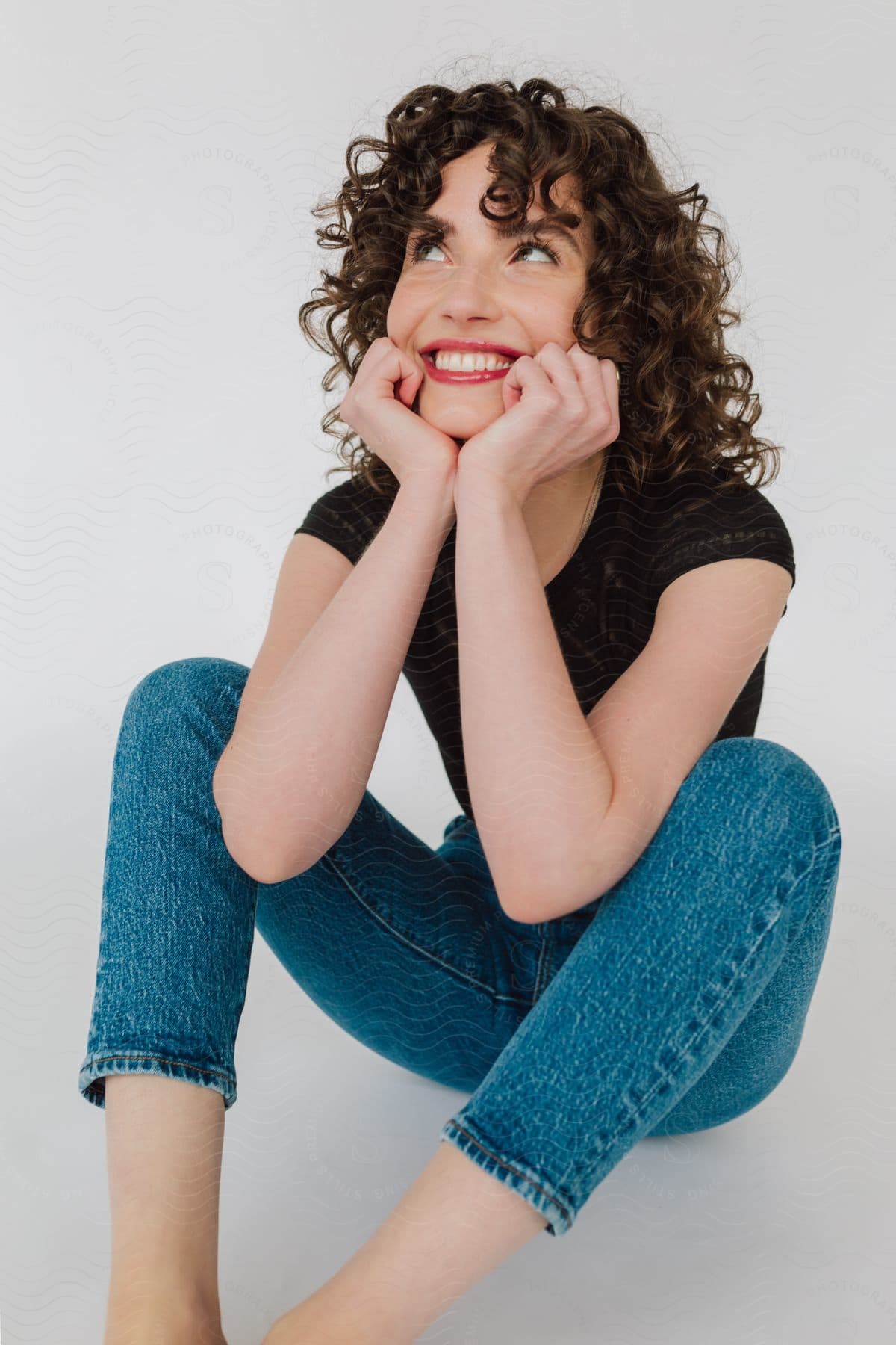 a woman smiles while sitting on the ground with her chin rest in her hands