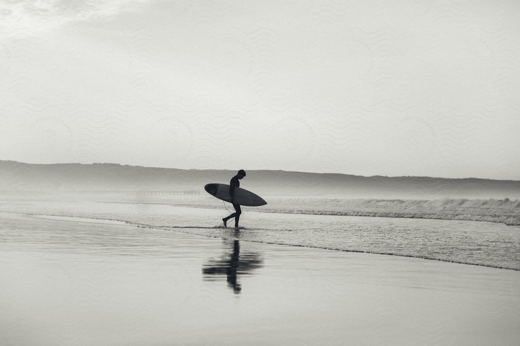 Man walking towards the sea while holding his surfboard.