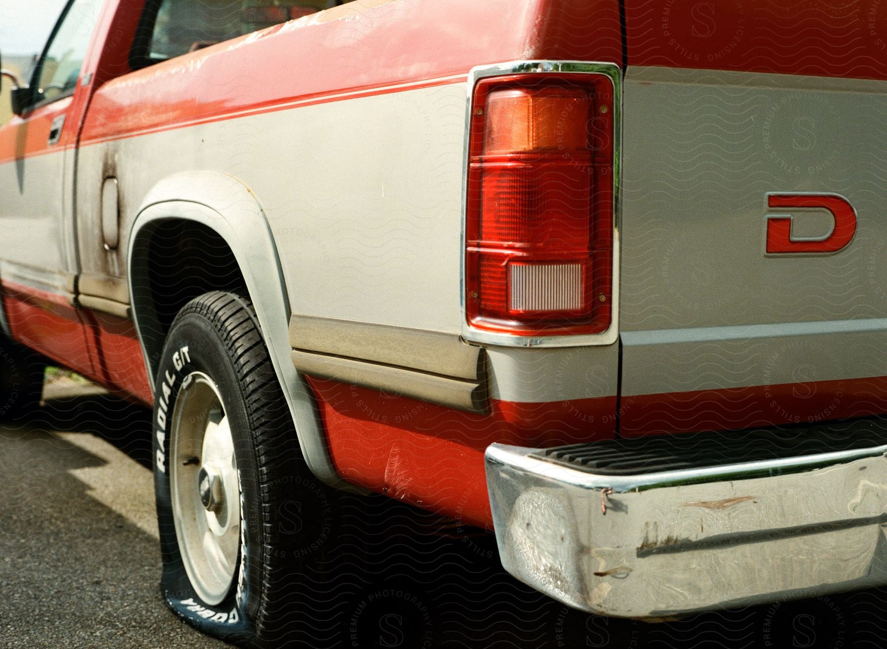 A red and grey dodge truck with a flat rear tire.