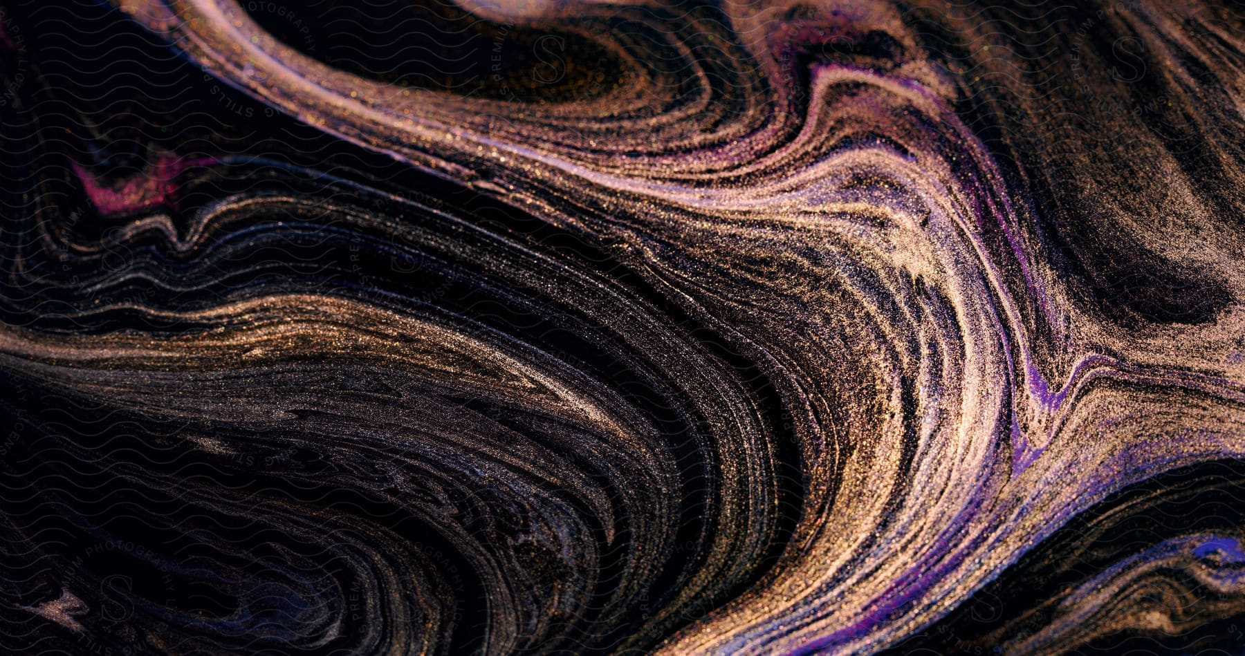 Close-up Of A Swirling Black And Gold Abstract With Gold Dust