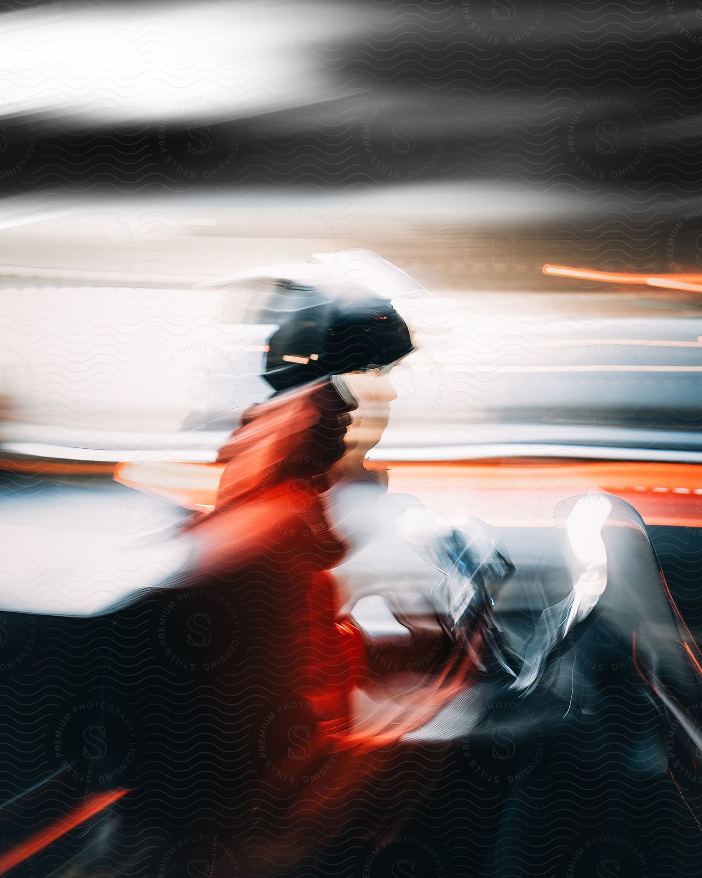 A cyclist is riding a motorcycle as blurry lights streak