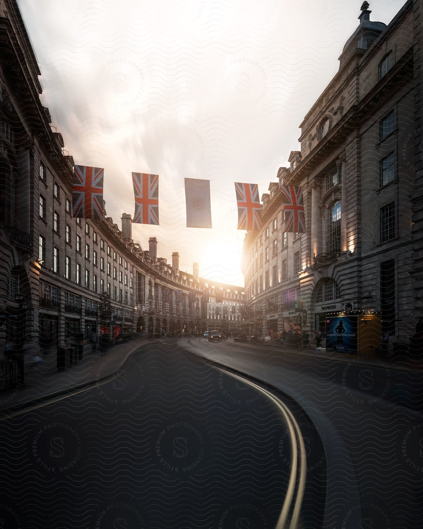 An English city street with Union Jack flags strung across it from building to building.