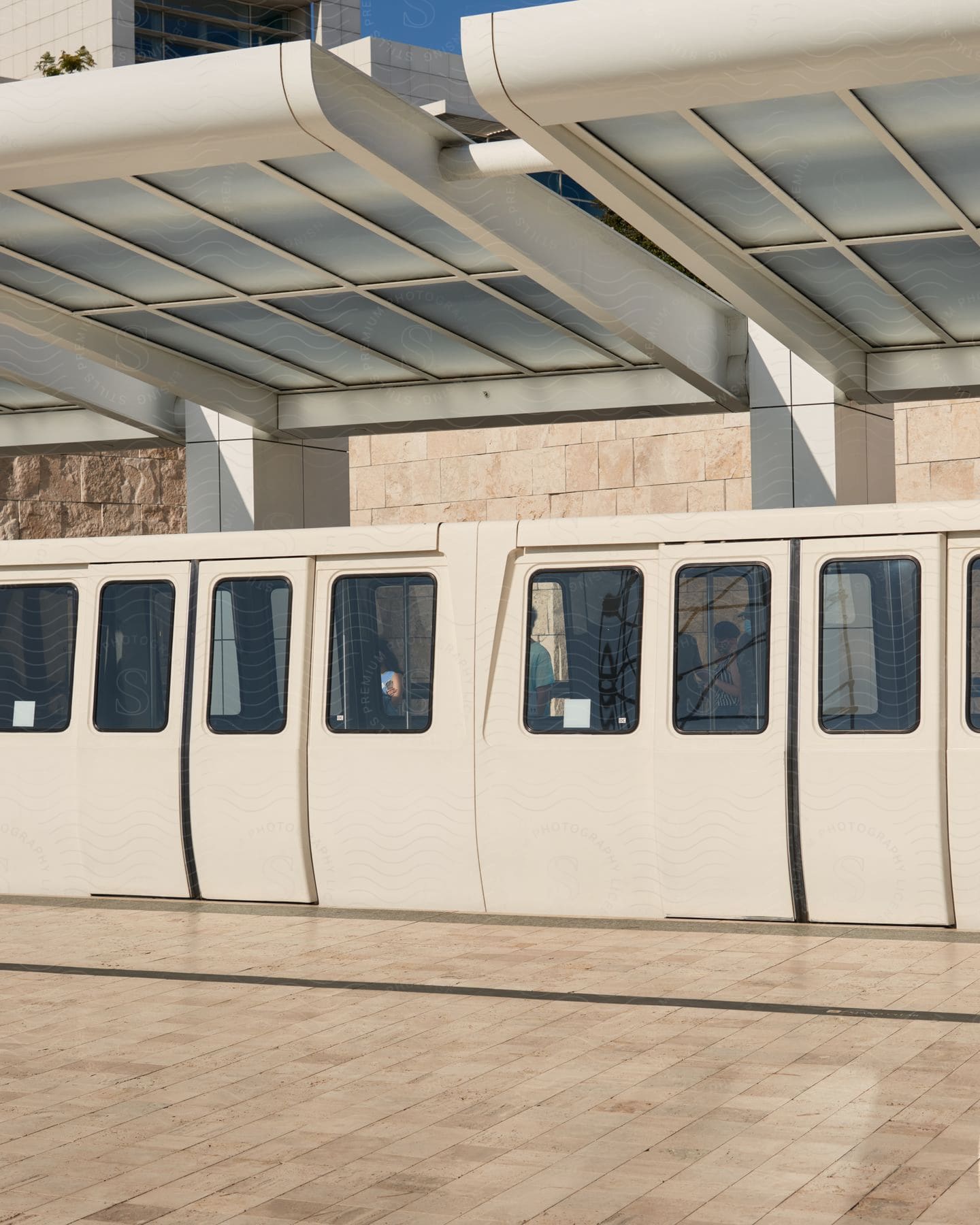 A subway train car sitting at a station outdoors in the sunlight