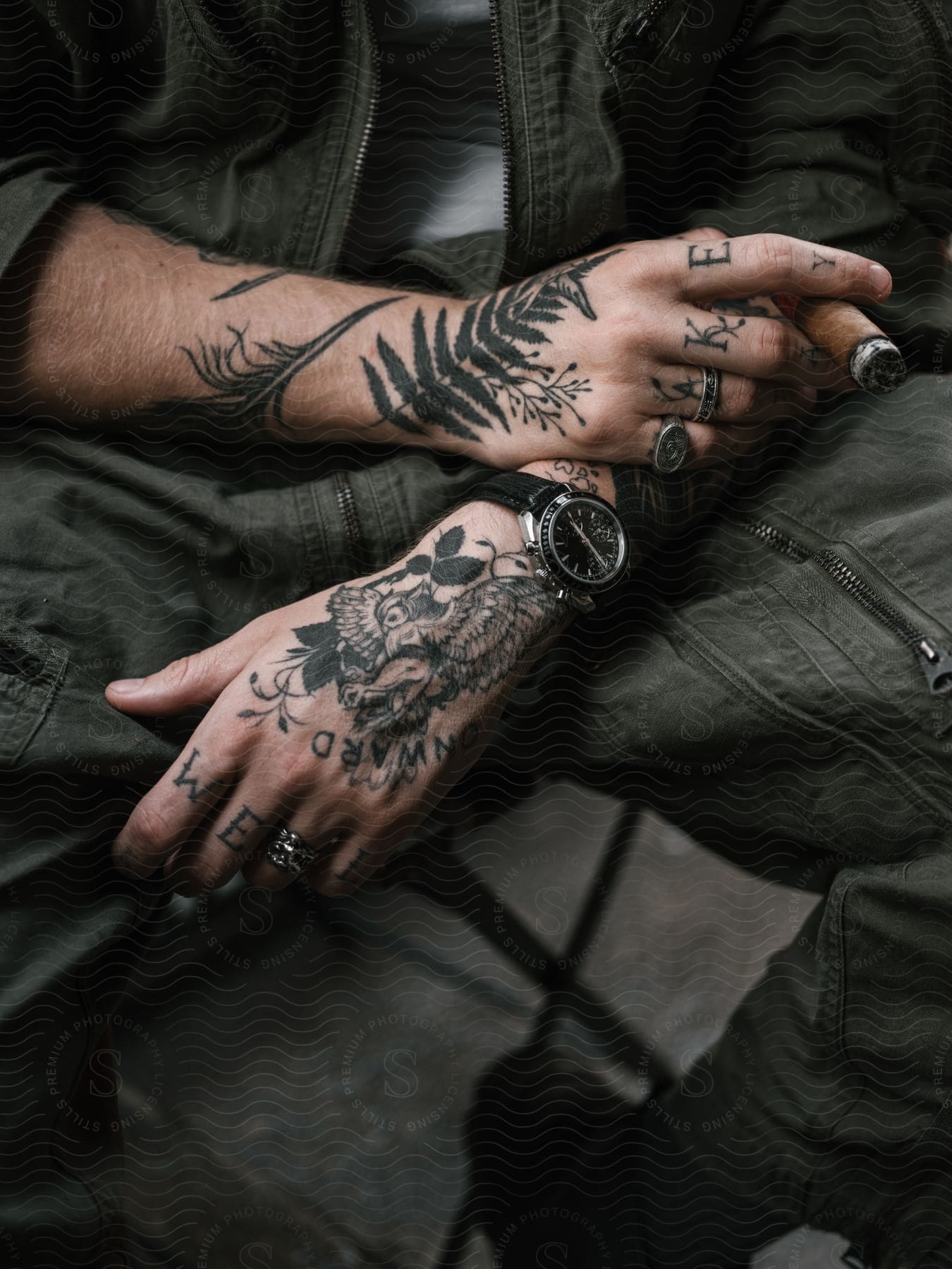 a man holds a cigar in his heavily tattooed hand