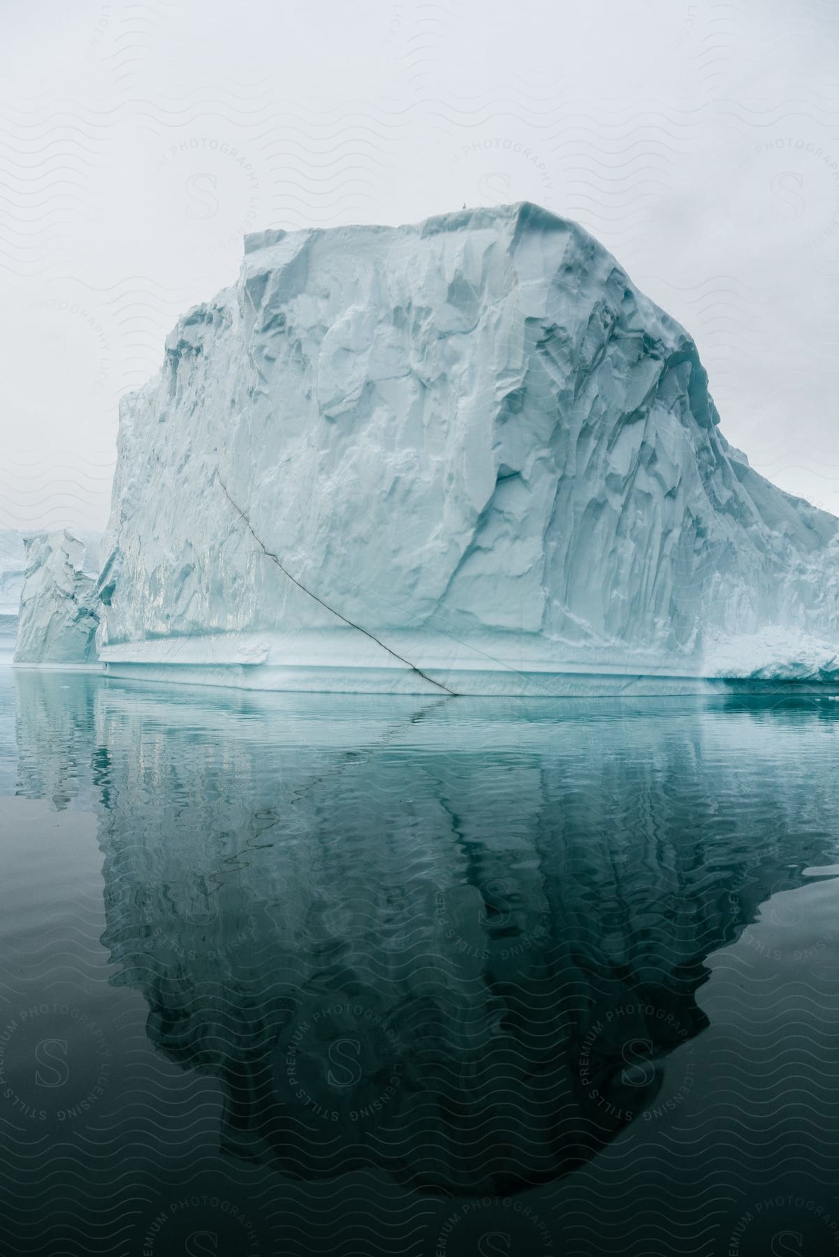 An iceberg of ice on top of the water that is reflecting your image.