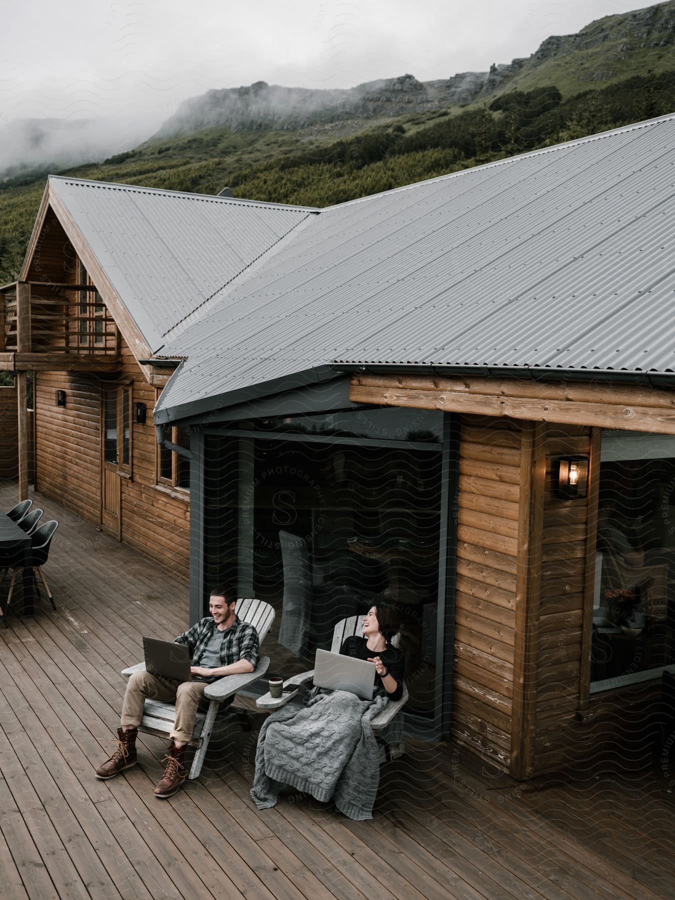 a man and woman work on their laptops while relaxing at a cabin