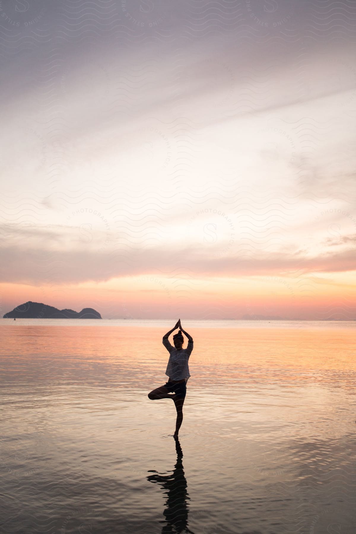 A woman doing yoga in the ocean at the edge of the water