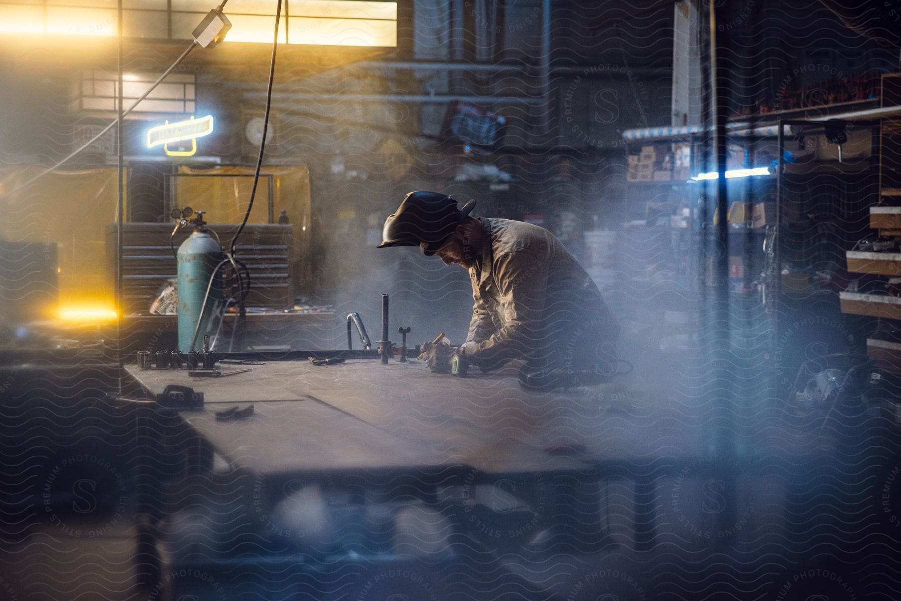 Welder using a construction pencil to write on a table in an indoor environment with welding tools.