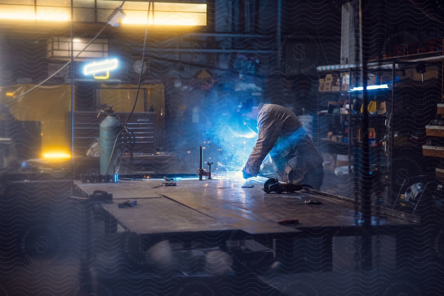 A welder in a machine shop lit by neon lights.