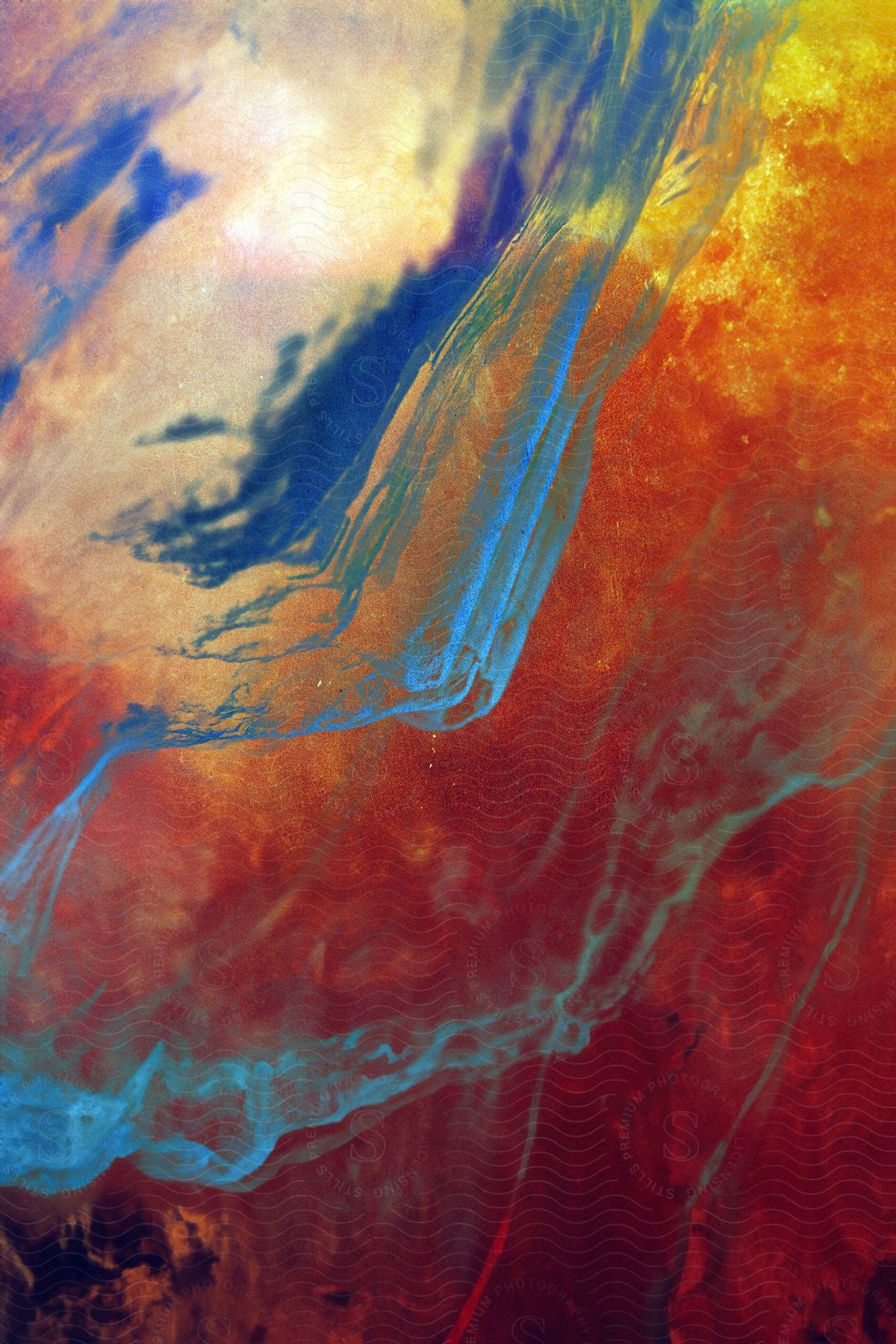 Blue streaks of liquid suspended in a reddish amber liquid.