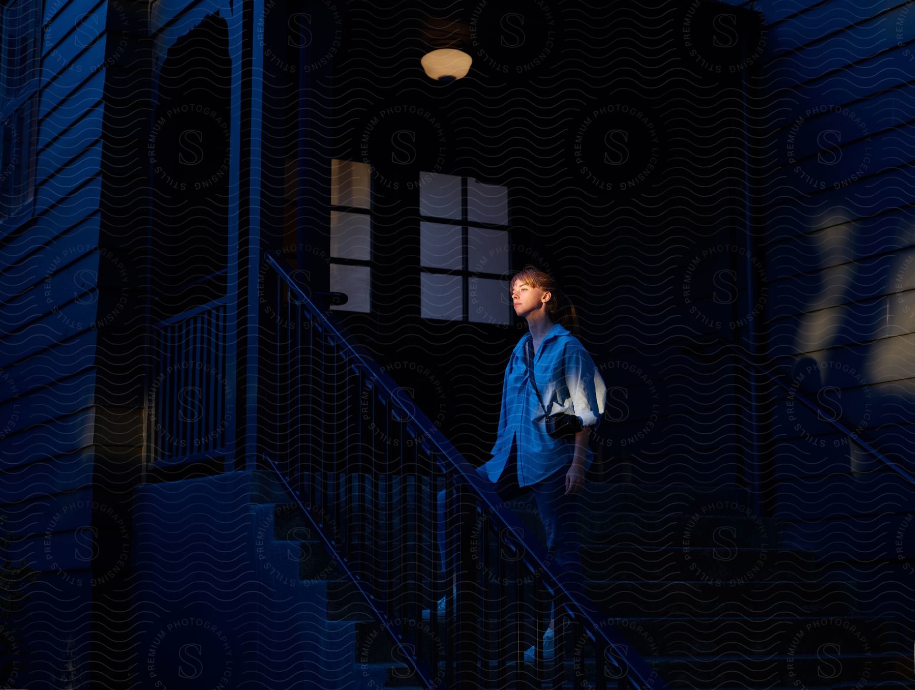 A woman standing on steps leading up to her house in the evening to a dimly lit porch