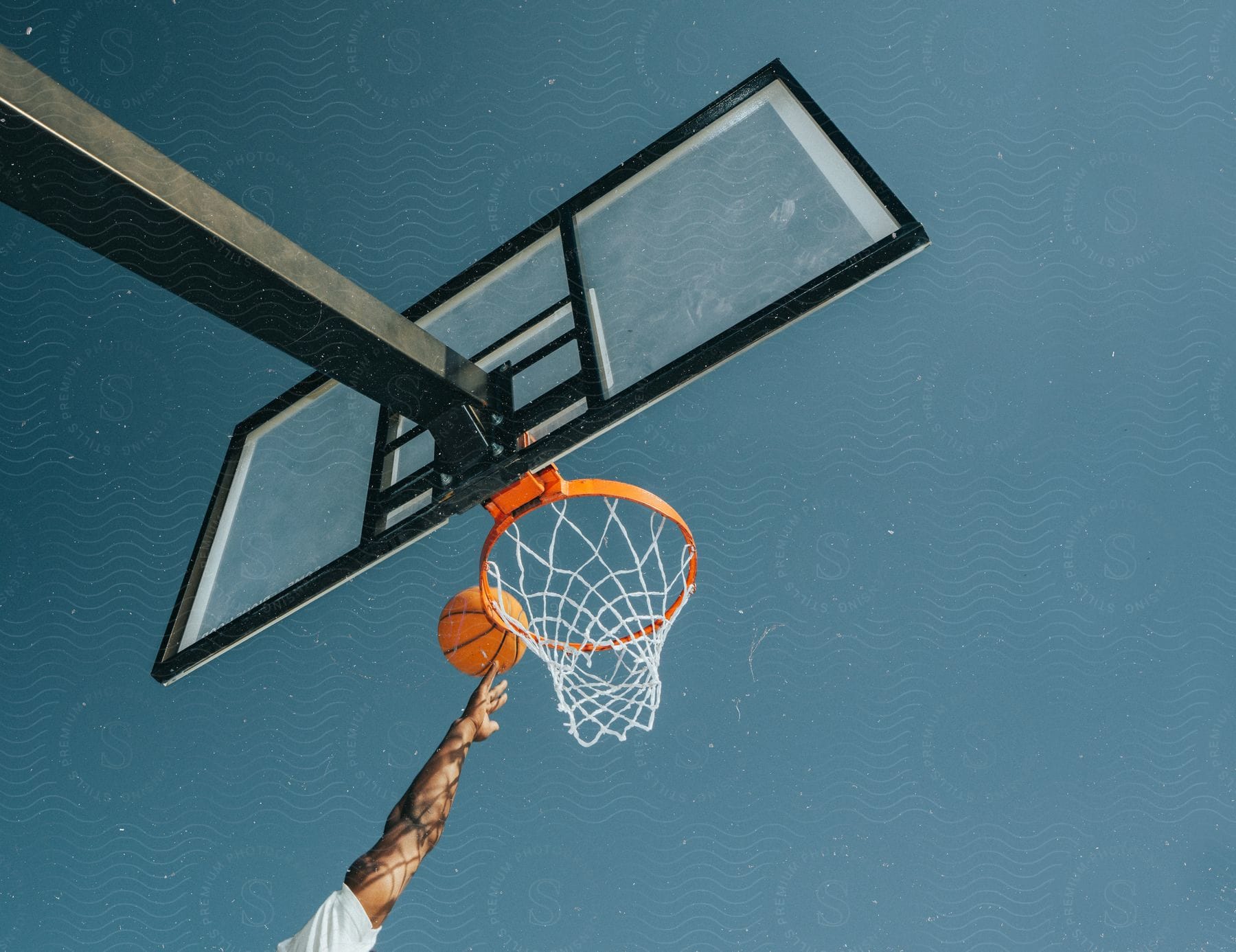 A person trying a slam dunk at the basketball hoop.