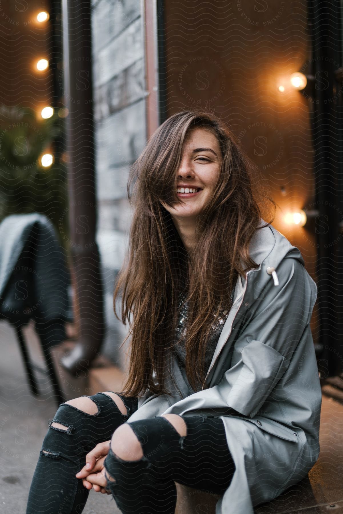 Young elegant woman, smiling and sitting in a posing position.