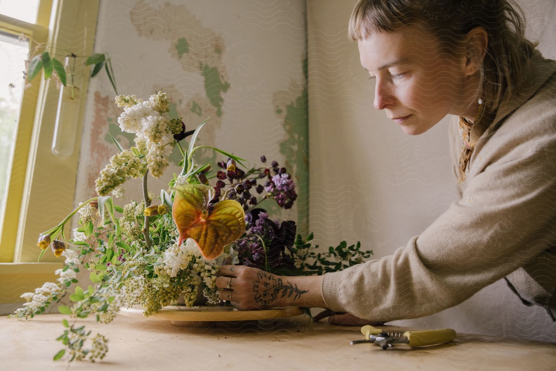 A woman setting up a floral display in a room