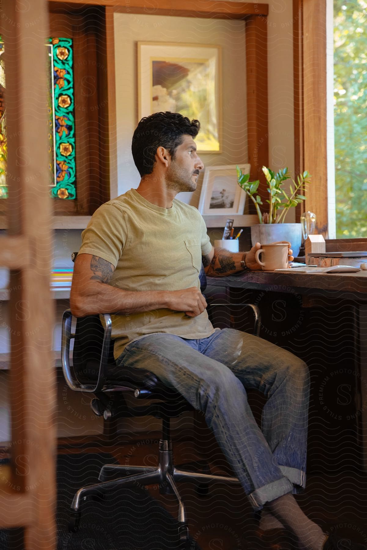 A man sitting in an office at a desk looking out the window thinking.