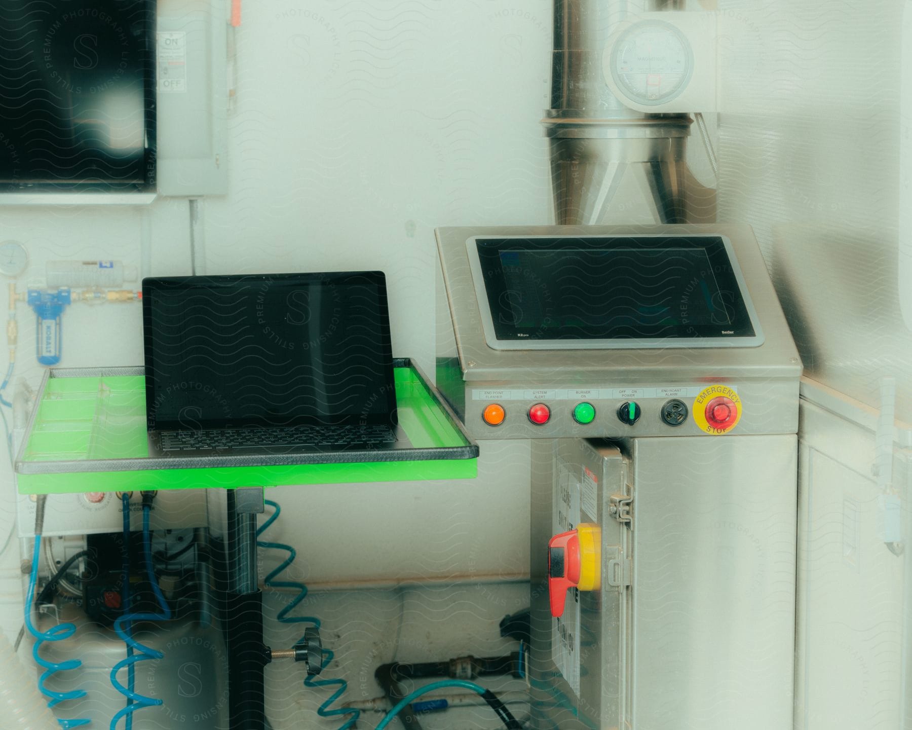 A black laptop sits on a green table next to a laboratory machine.