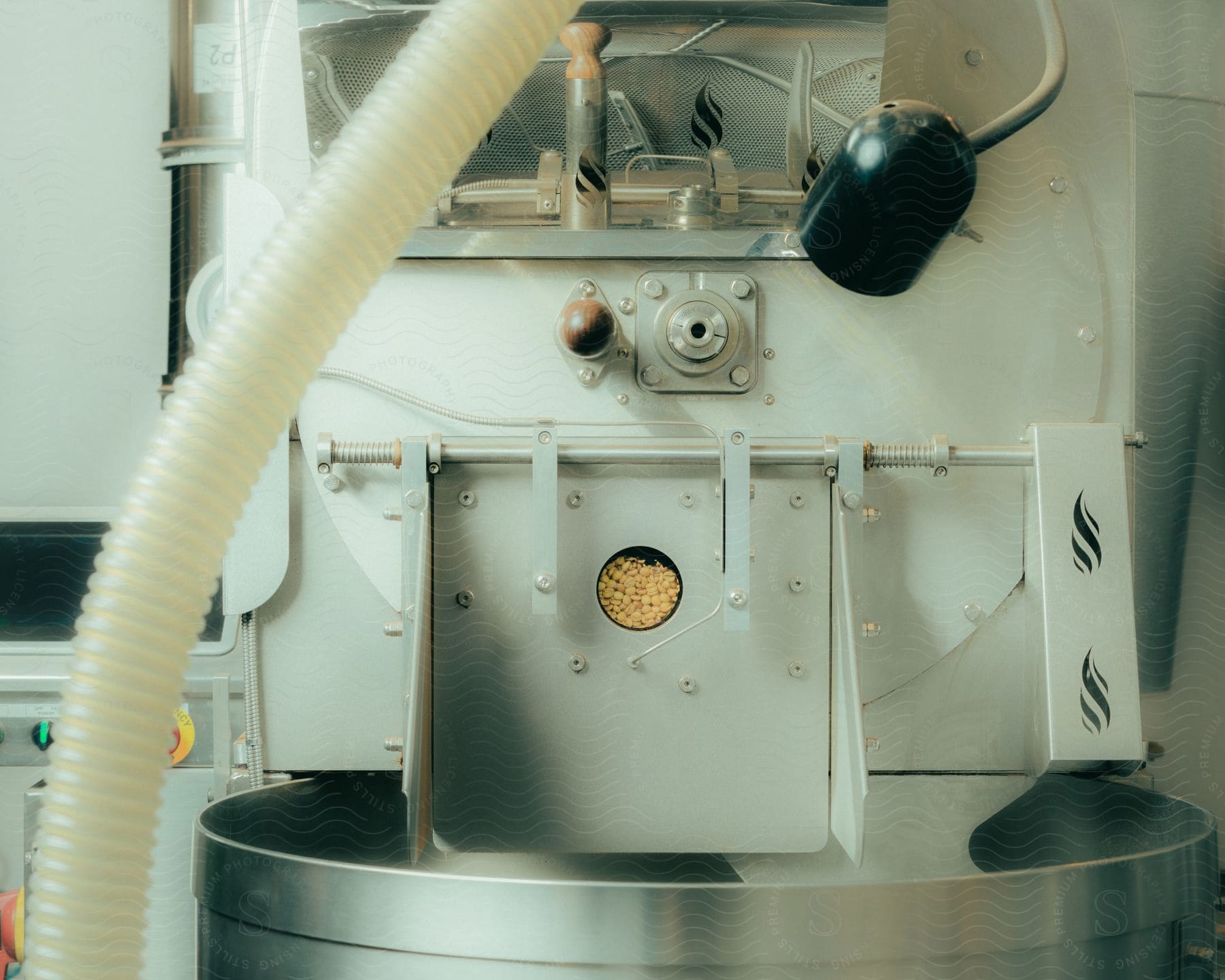 A pale green industrial machine with a grain chute opening to a vat.