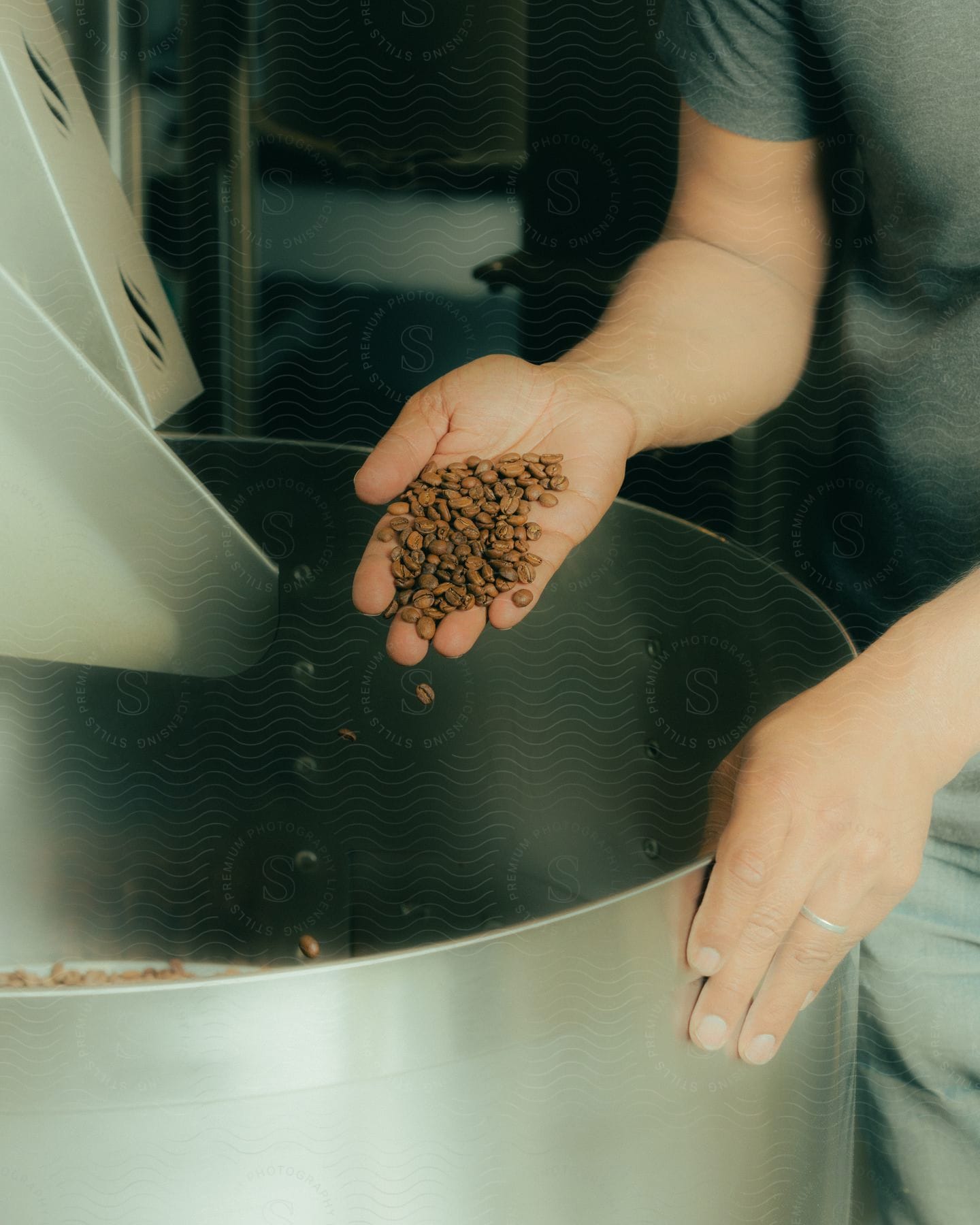 a man holding some coffee beans while most drops in a big bowl inside the kitchen