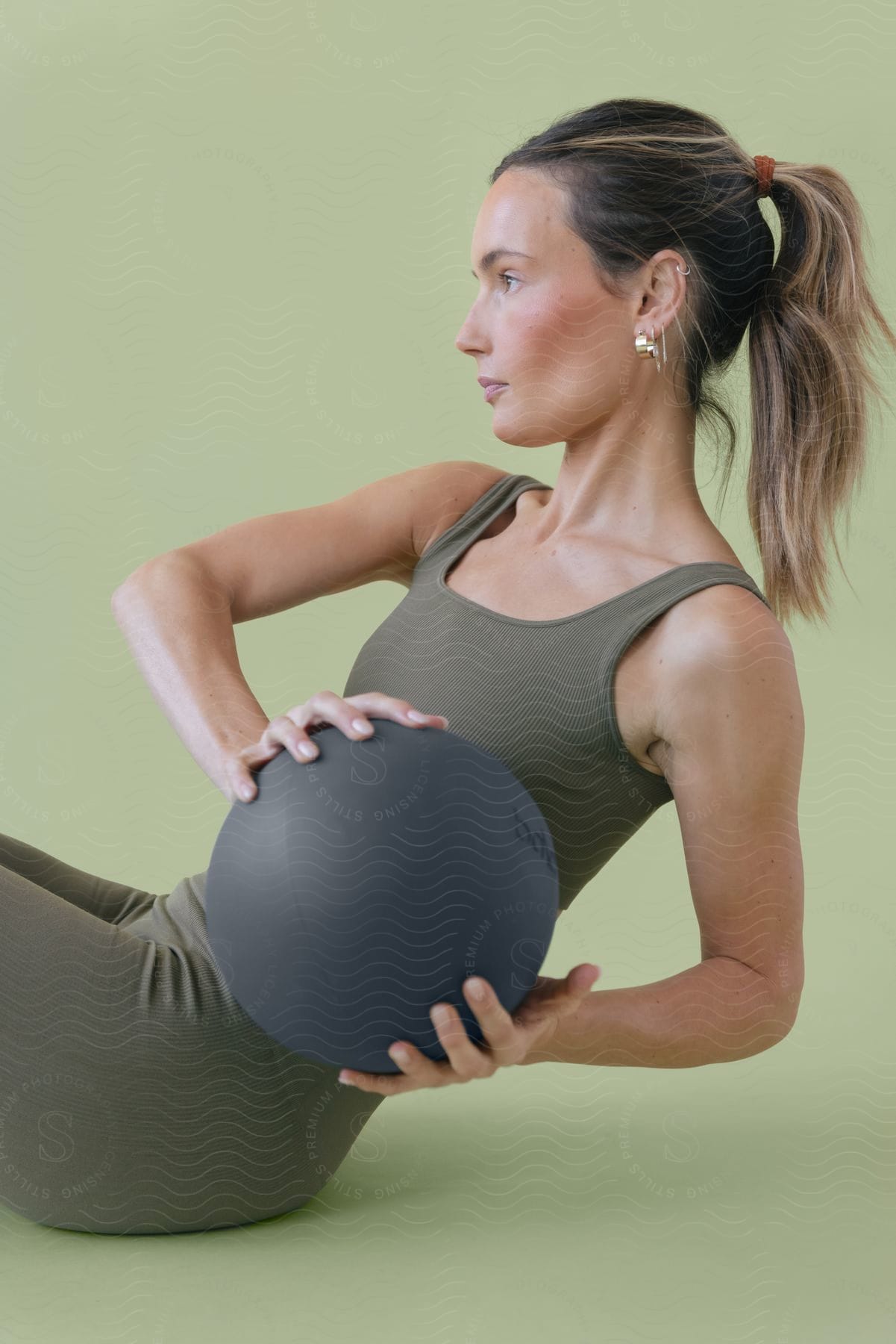 A woman doing yoga stretches while holding a weighted ball